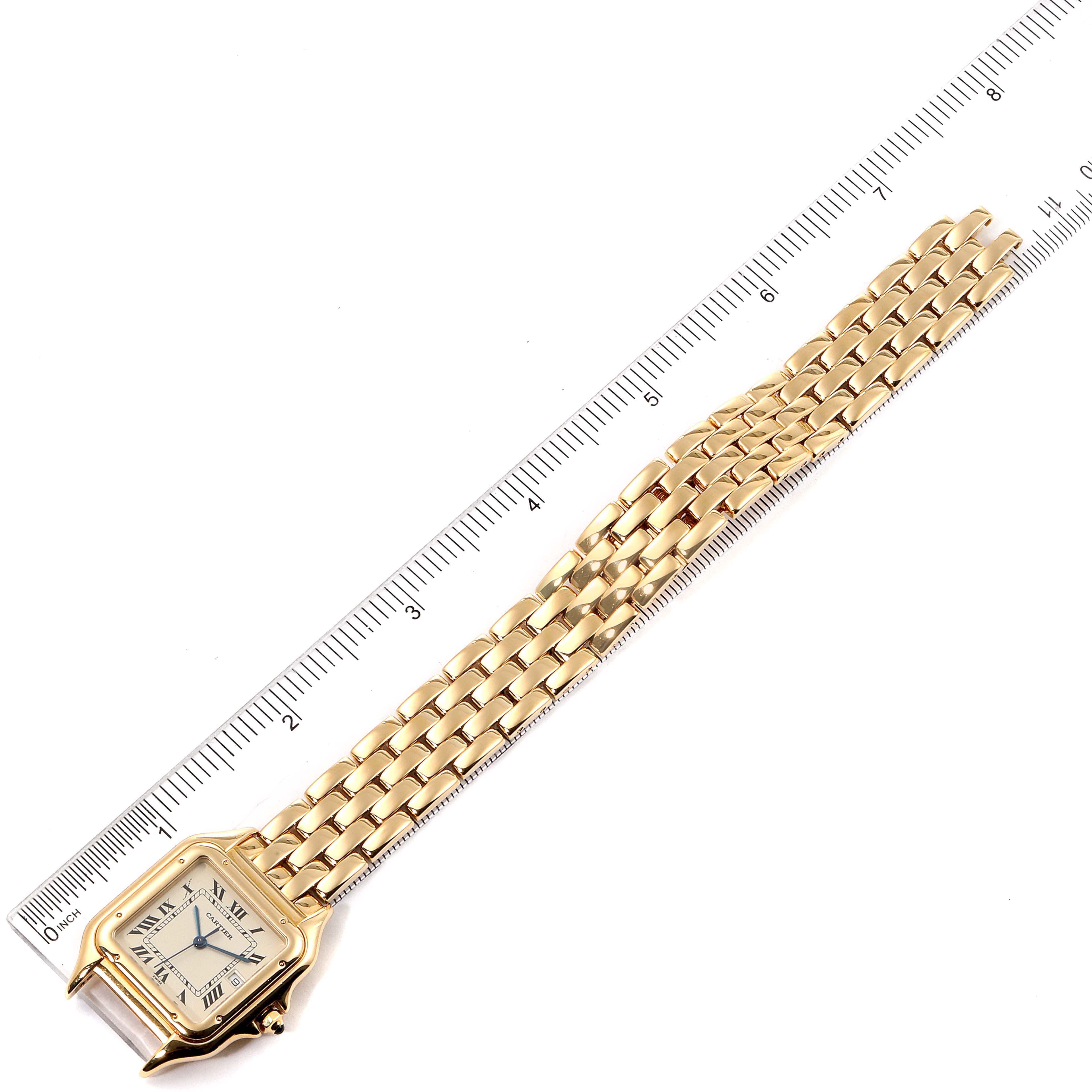 This image shows a Panthere model by Cartier watch, displaying the face and entire gold bracelet, laid next to a ruler.