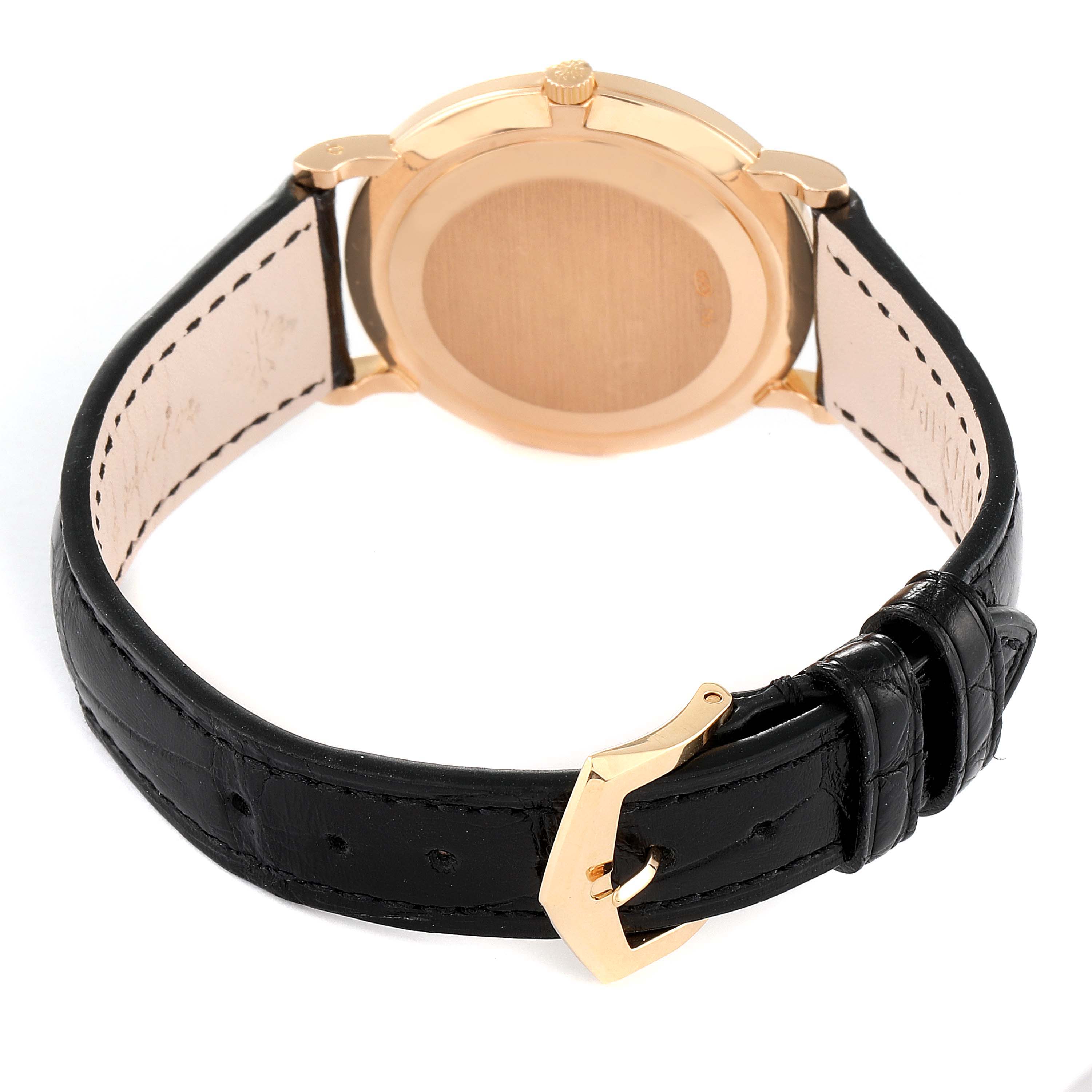 The image shows the back view of a Patek Philippe Calatrava 5022R Men
s Rose Gold White Dial 5022R Men
s Rose Gold White Dial watch, highlighting its golden case and black leather strap with a buckle.
