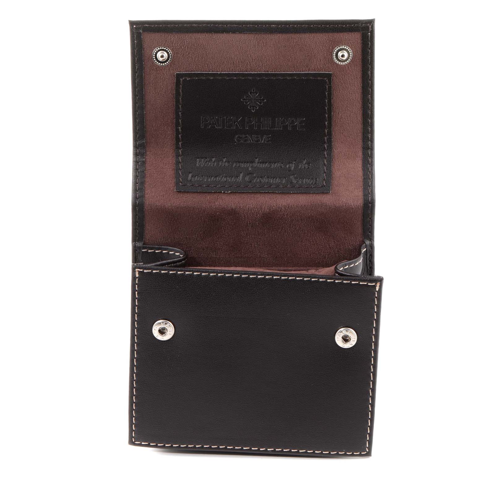 The image shows an open black case with a brown interior for a Patek Philippe Calatrava 5134G Men
s White Gold White Dial 5134G Men
s White Gold White Dial watch, featuring the brand
s logo inside.