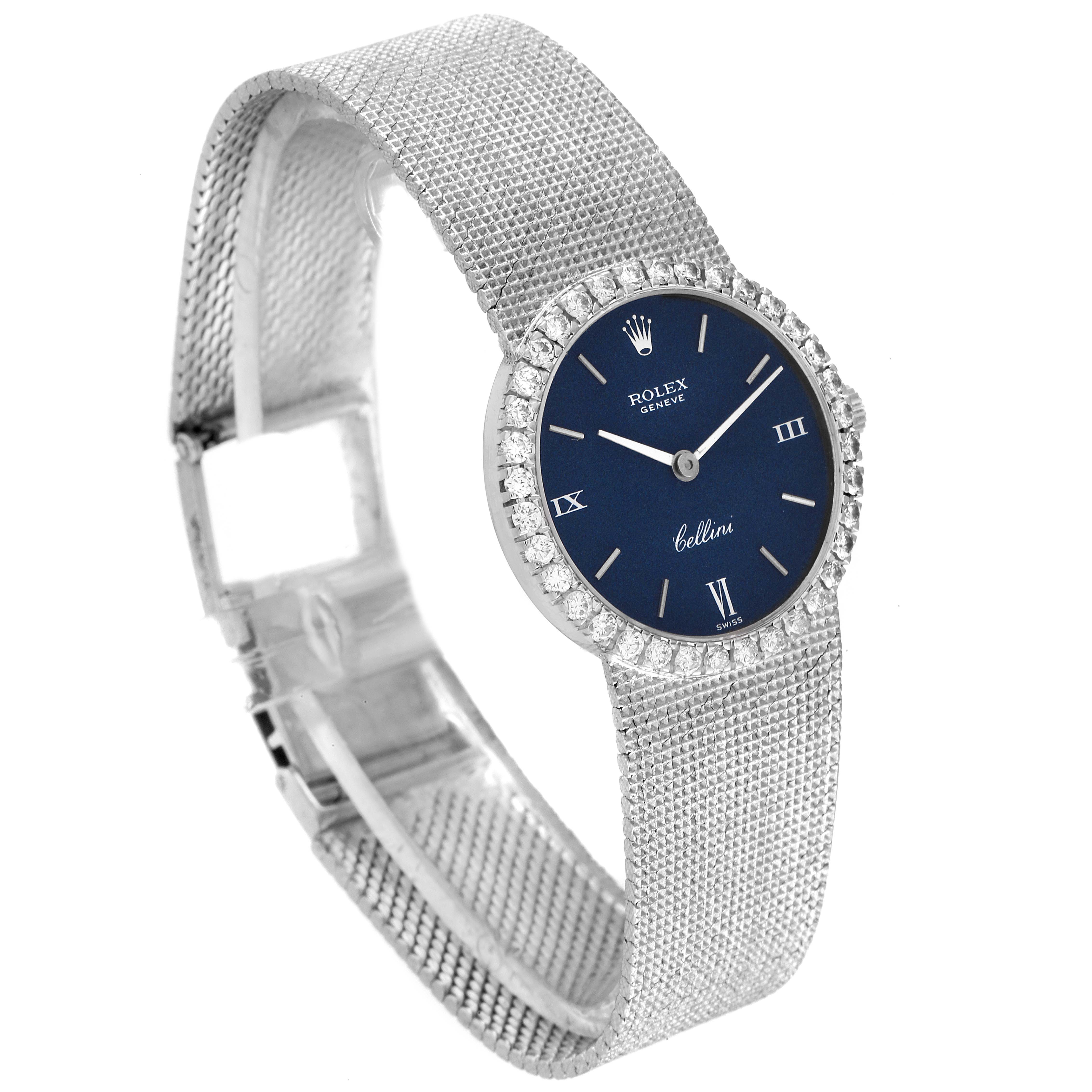 The image shows a Rolex Cocktail 3812 Women
s White Gold Blue Dial 3812 Women
s White Gold Blue Dial model watch with a blue dial, diamond bezel, and a mesh bracelet, viewed from an angled perspective.