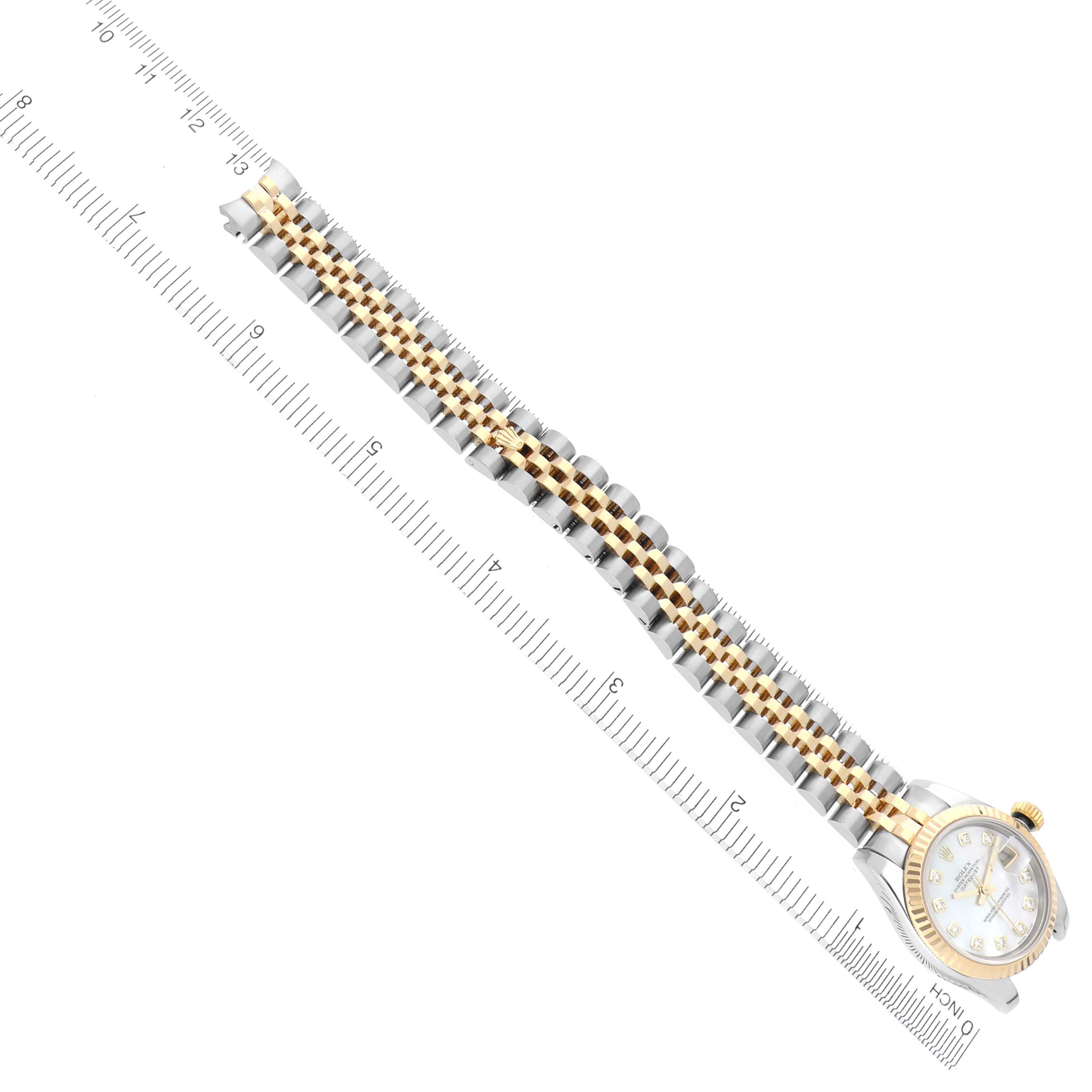 The Rolex Datejust 179173 Women's Steel and Gold (two tone) Mother of Pearl Dial 179173 Women's Steel and Gold (two tone) Mother of Pearl Dial watch is shown diagonally from above, highlighting the face, bezel, and bracelet against a ruler.