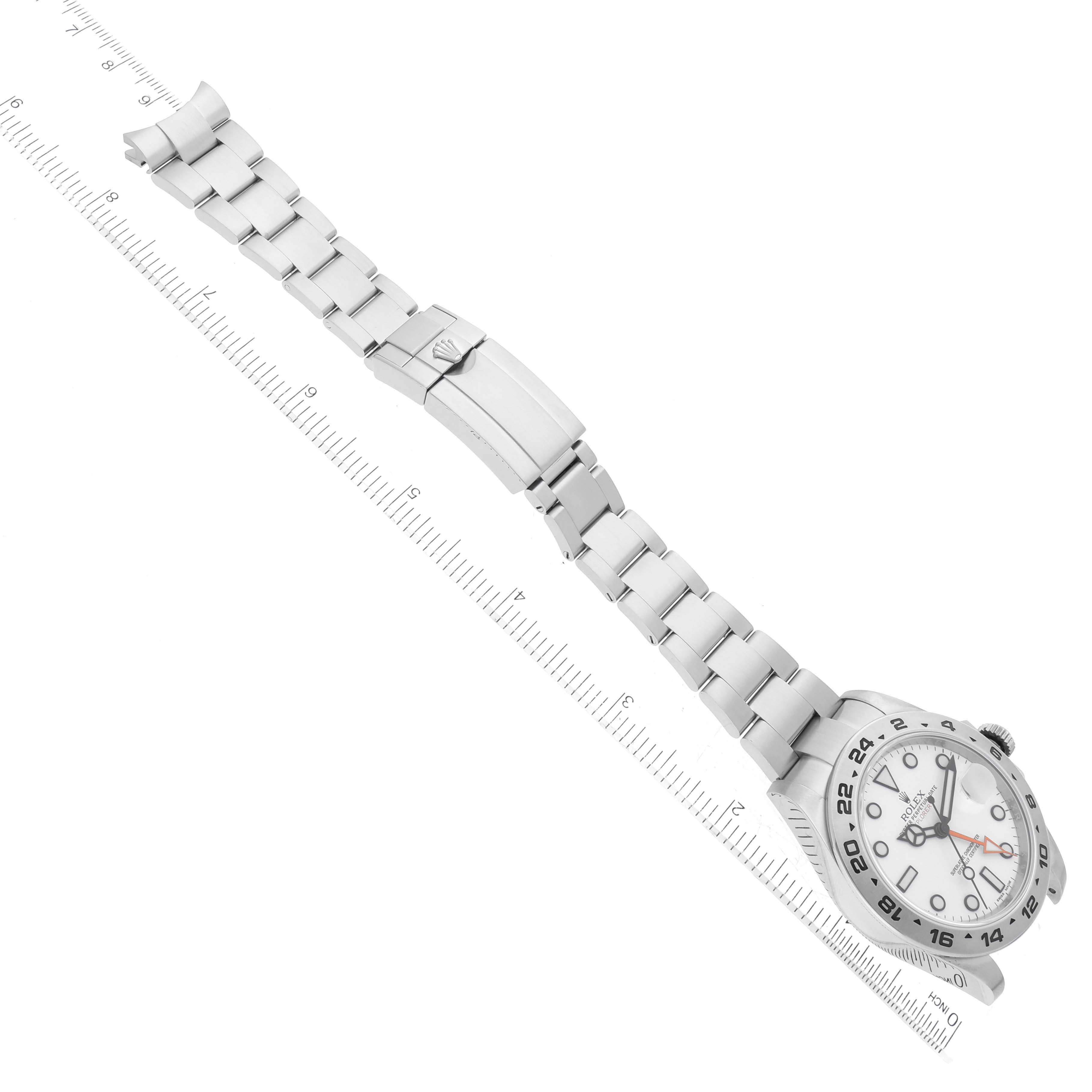 The image shows a top view of a Rolex Explorer 216570 Men
s Stainless Steel White Dial 216570 Men
s Stainless Steel White Dial watch, displaying its face, bezel, and metal bracelet placed alongside a ruler.