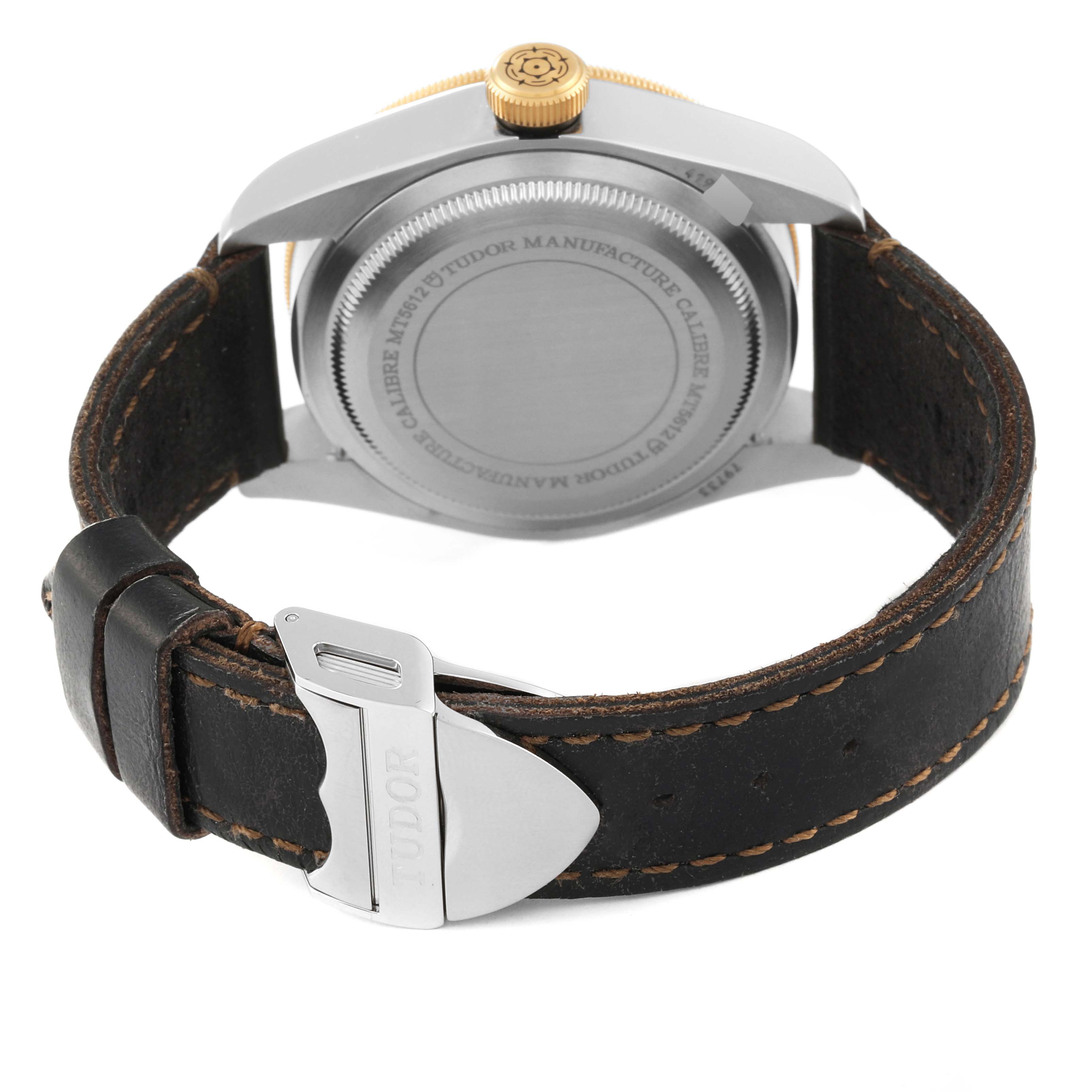 This image shows the back of the Tudor Heritage Black Bay 79733N Men
s Steel and Gold (two tone) Black Dial 79733N Men
s Steel and Gold (two tone) Black Dial watch, highlighting the case back, crown, and leather strap with a clasp.