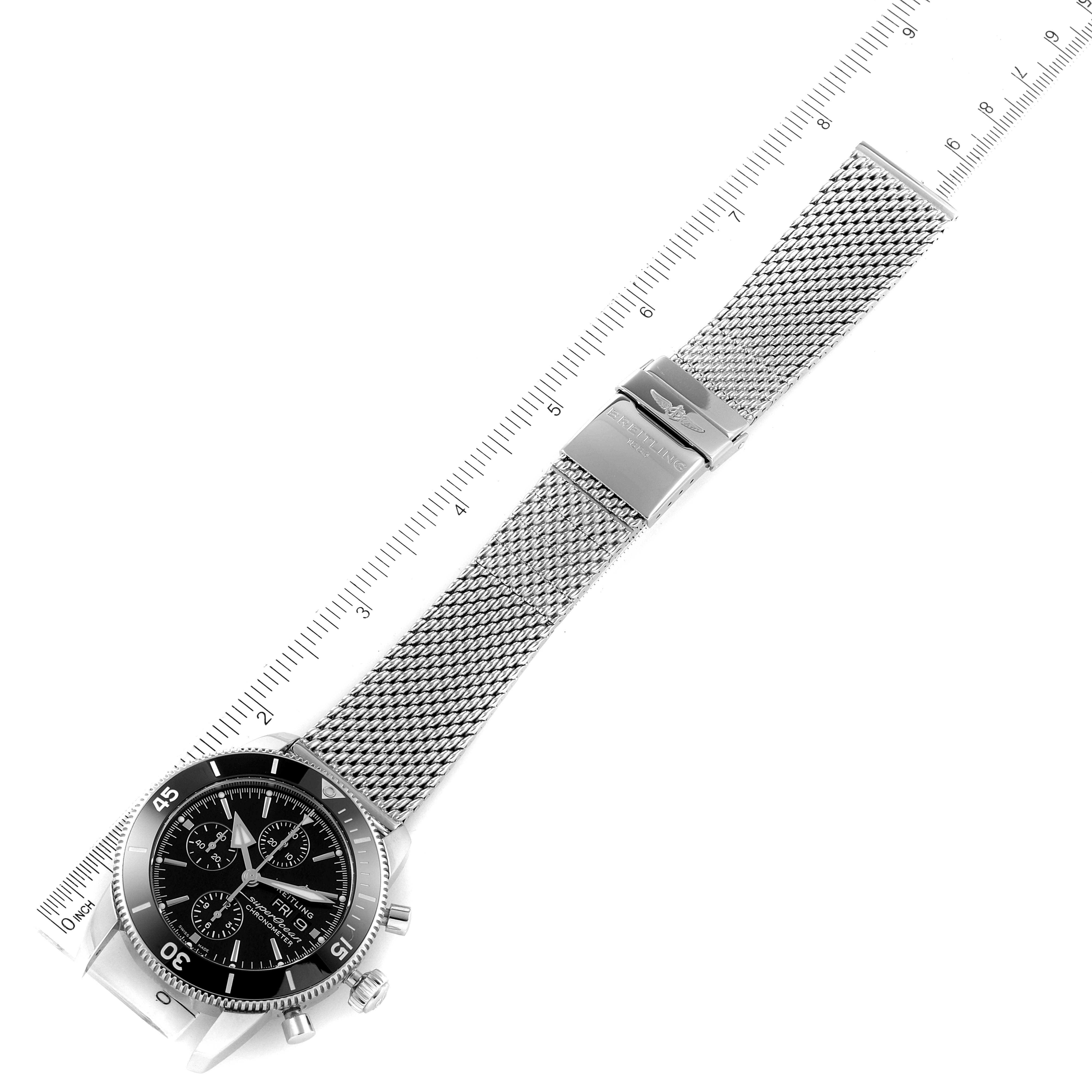The Breitling Superocean A13320 Men's Stainless Steel Black Dial A13320 Men's Stainless Steel Black Dial watch is shown from an oblique top-down angle, highlighting the face, mesh strap, clasp, and a ruler for scale.