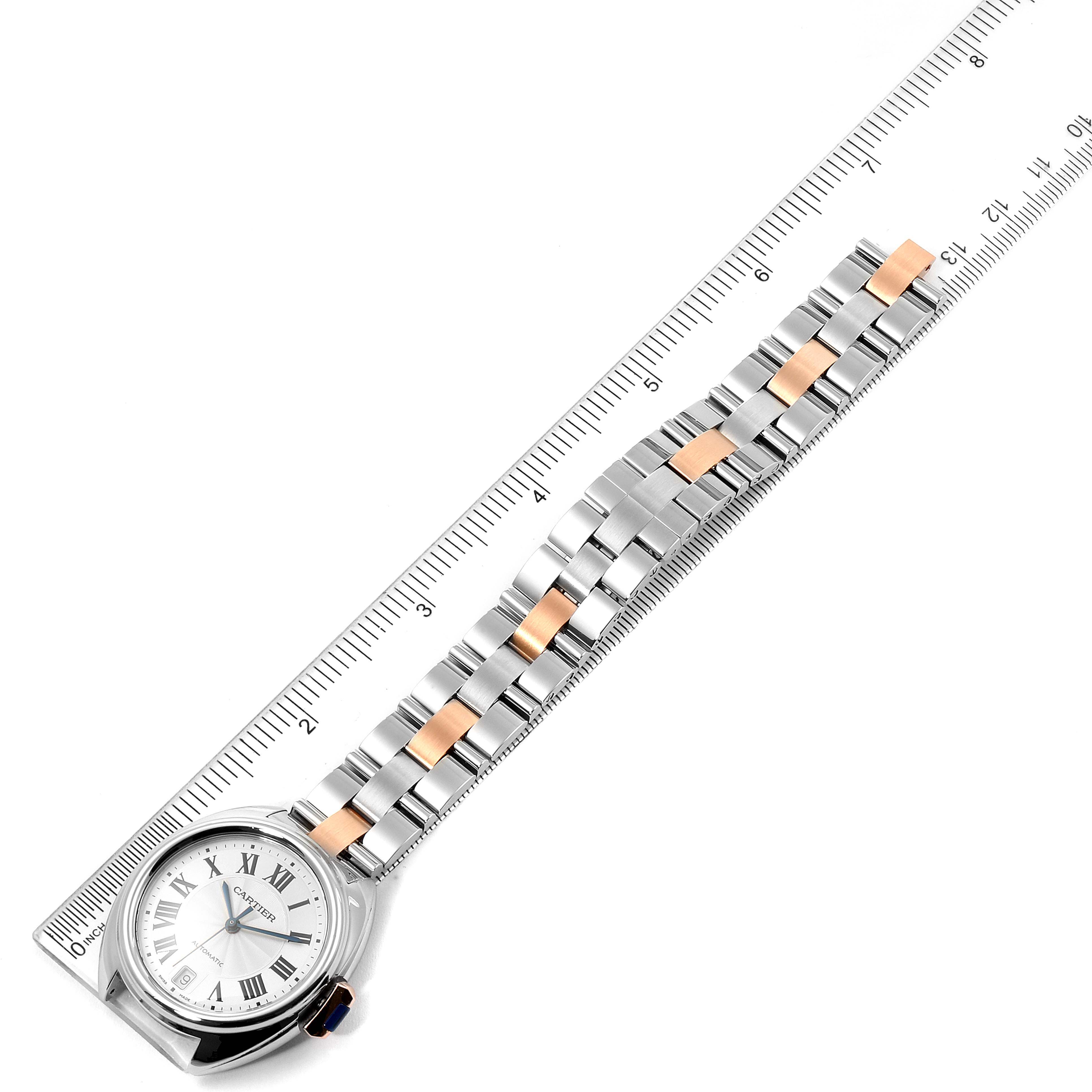 The Cartier Cle WSCL0003 Women's Steel and Gold (two tone) Blue Dial WSCL0003 Women's Steel and Gold (two tone) Blue Dial watch is shown at an angled top view, displaying its face, bezel, and two-tone bracelet against a ruler for scale.