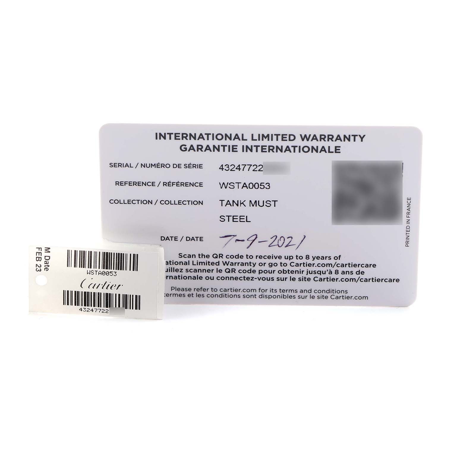 The image shows a Cartier Tank Must WSTA0053 Men's Stainless Steel Silver Dial warranty card and tag with serial and reference numbers visible.