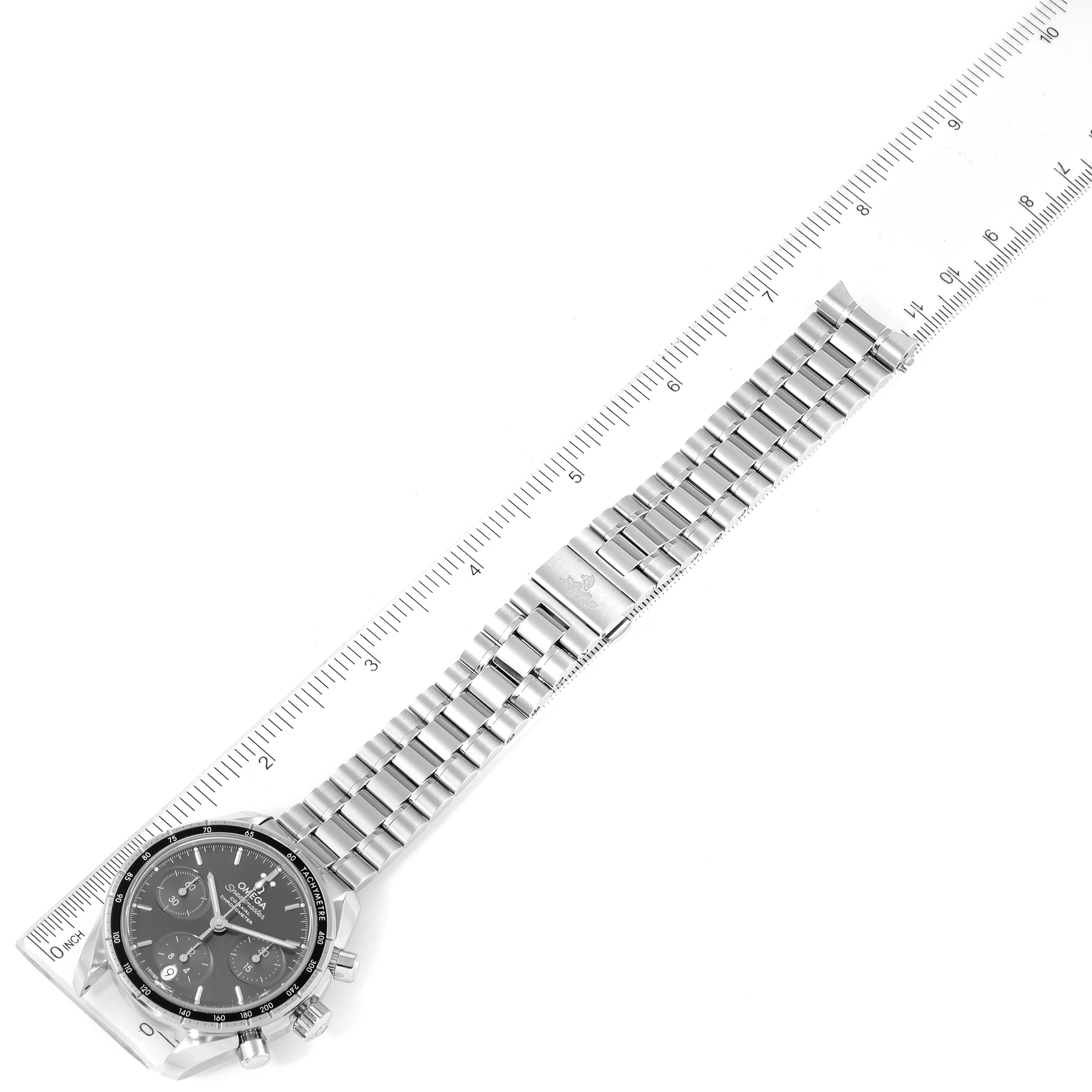 The Omega Speedmaster 324.30.38.50.06.001 Men
s Stainless Steel Grey Dial 324.30.38.50.06.001 Men
s Stainless Steel Grey Dial watch is shown from a top-down angle alongside a ruler, highlighting its bracelet and clasp.