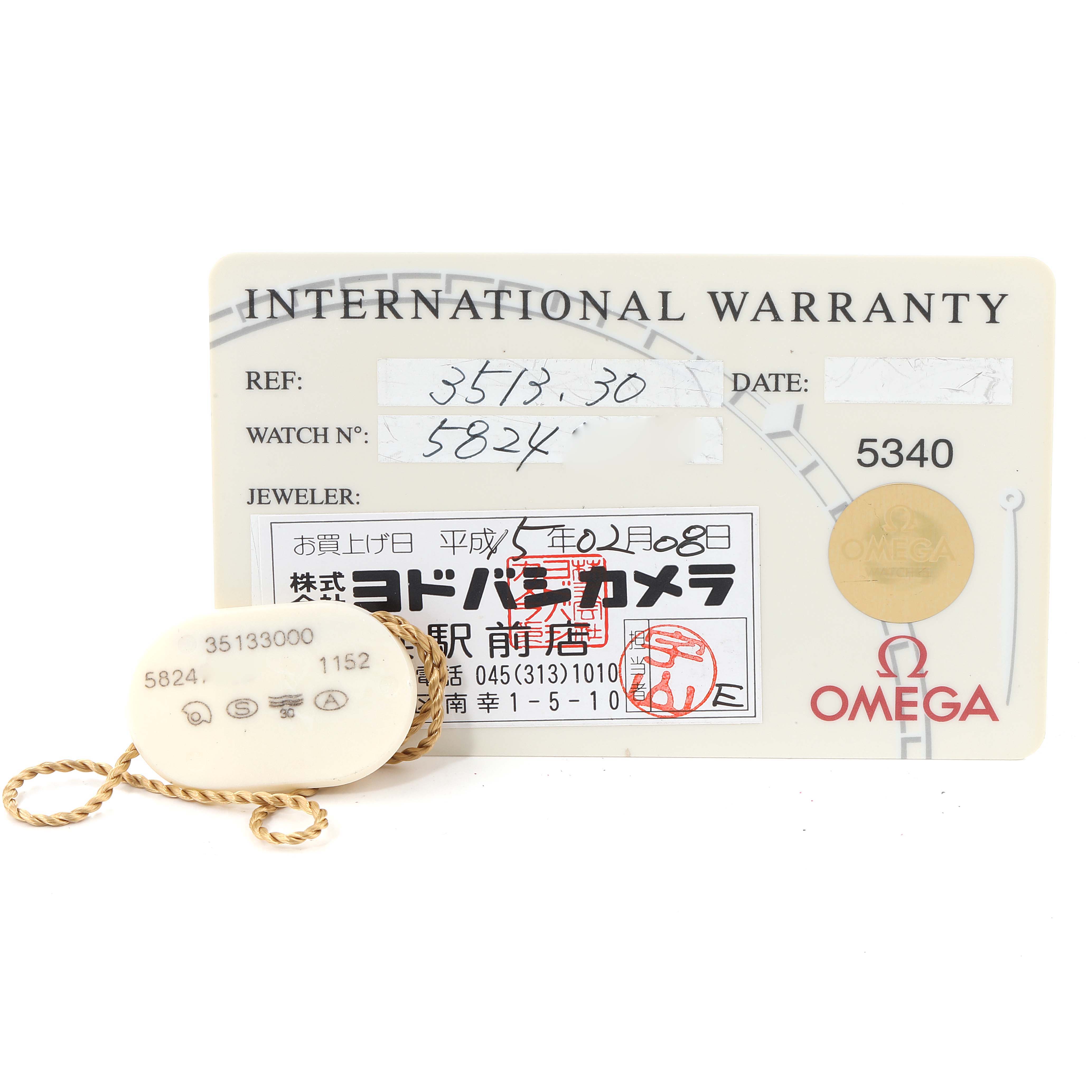 This image shows a warranty card and tag for an Omega Speedmaster 3513.30.00 Men
s Stainless Steel Silver Dial 3513.30.00 Men
s Stainless Steel Silver Dial watch, viewed from above.