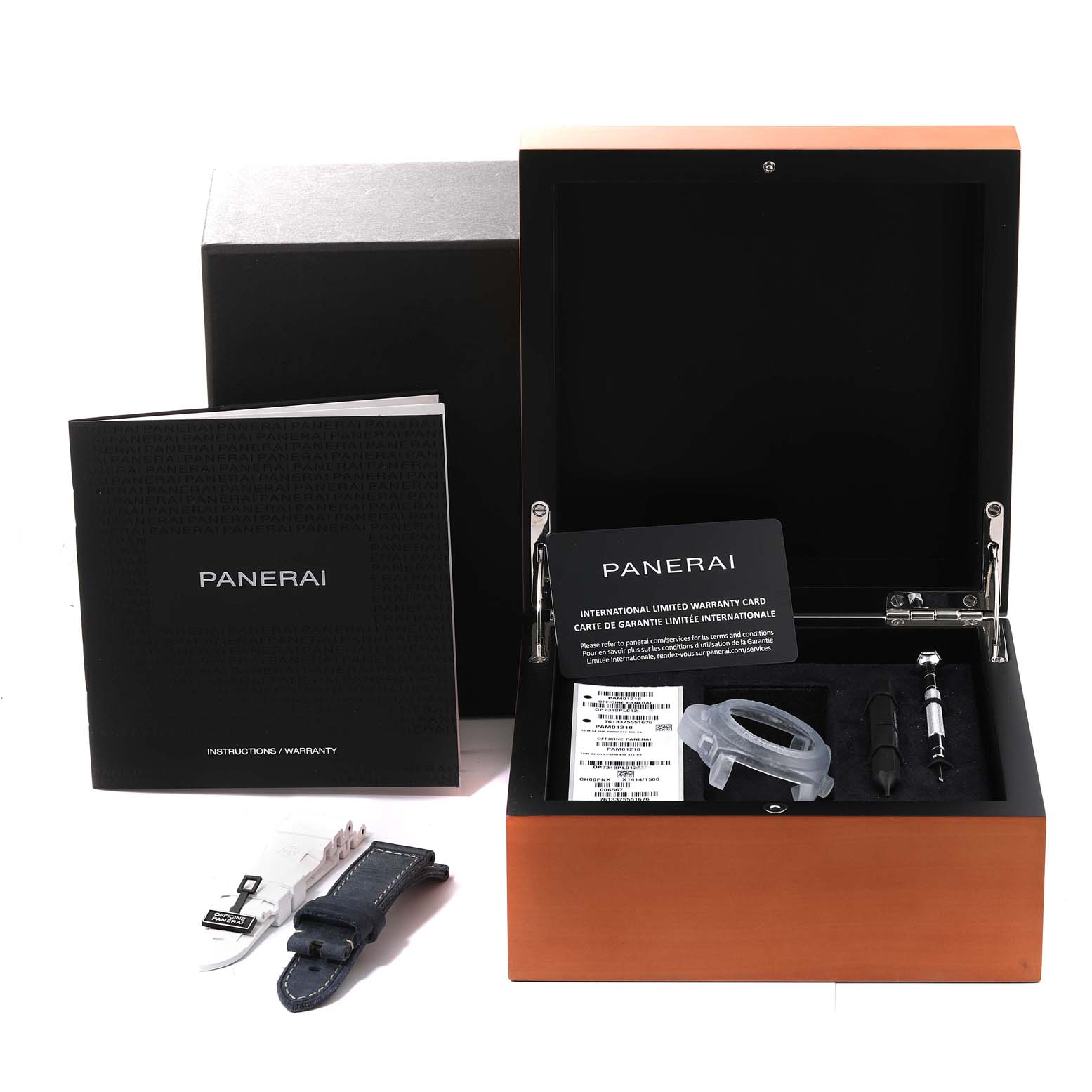 The image shows the open packaging of a Panerai Luminor PAM01218 Men
s Stainless Steel White Dial PAM01218 Men
s Stainless Steel White Dial with its accessories, including a strap, tools, and documentation.