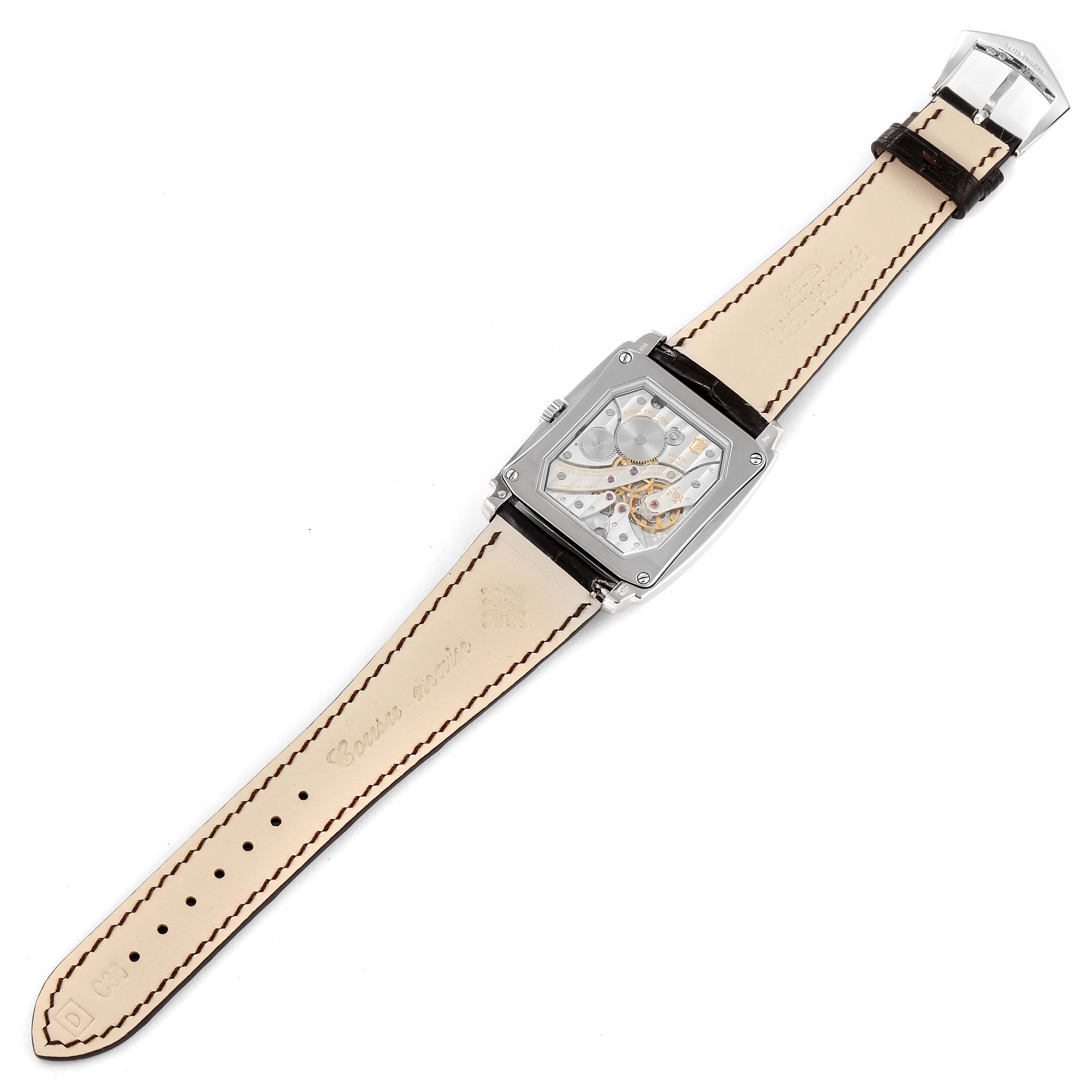 The Patek Philippe Gondolo 5124G-001 Men's White Gold Pink Dial 5124G-001 Men's White Gold Pink Dial watch is shown from a top-down angle, displaying its face, transparent case back, and leather strap.