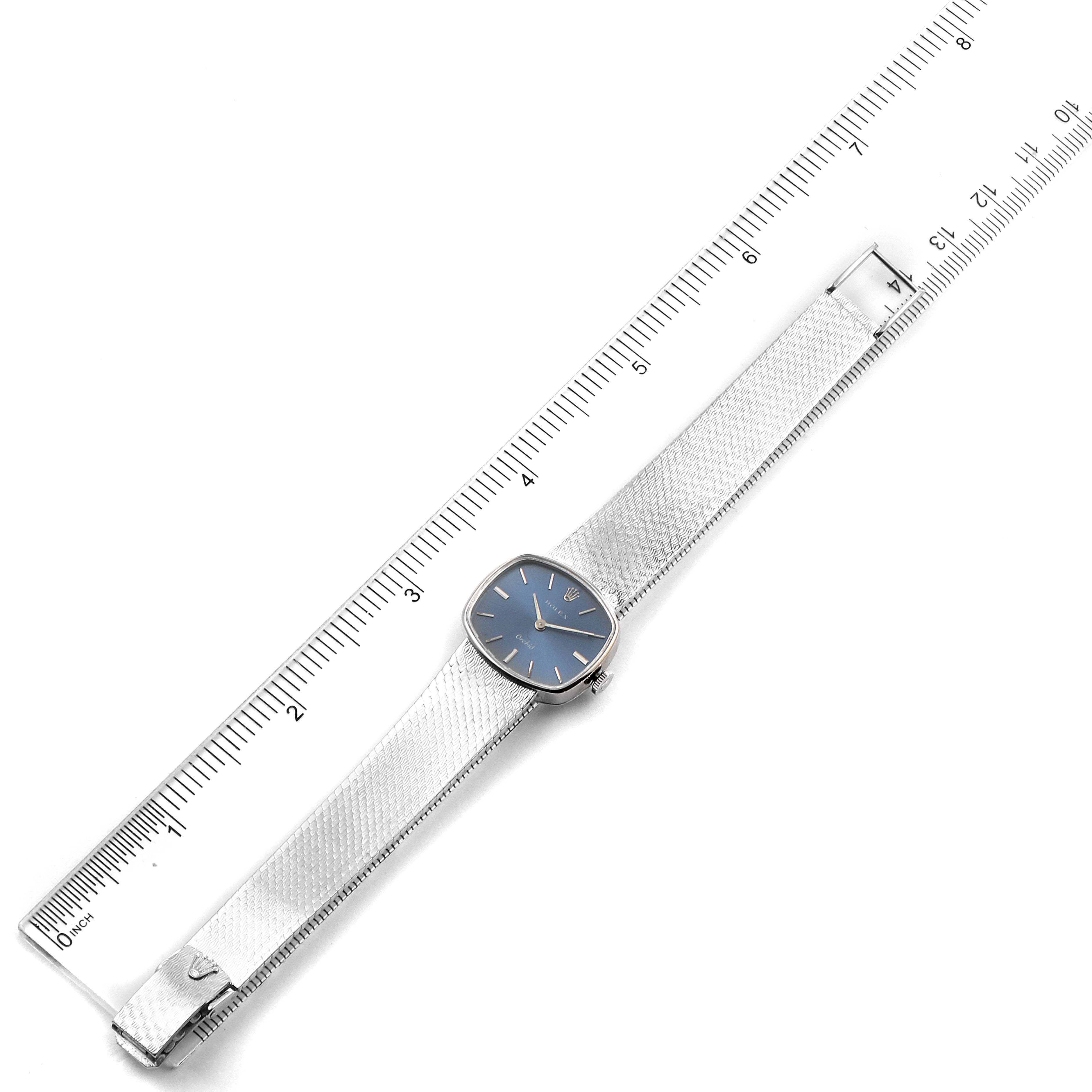 The Rolex Cocktail 2673 Women's White Gold Blue Dial 2673 Women's White Gold Blue Dial model watch with a blue dial and full stainless steel strap is placed alongside a ruler for scale.