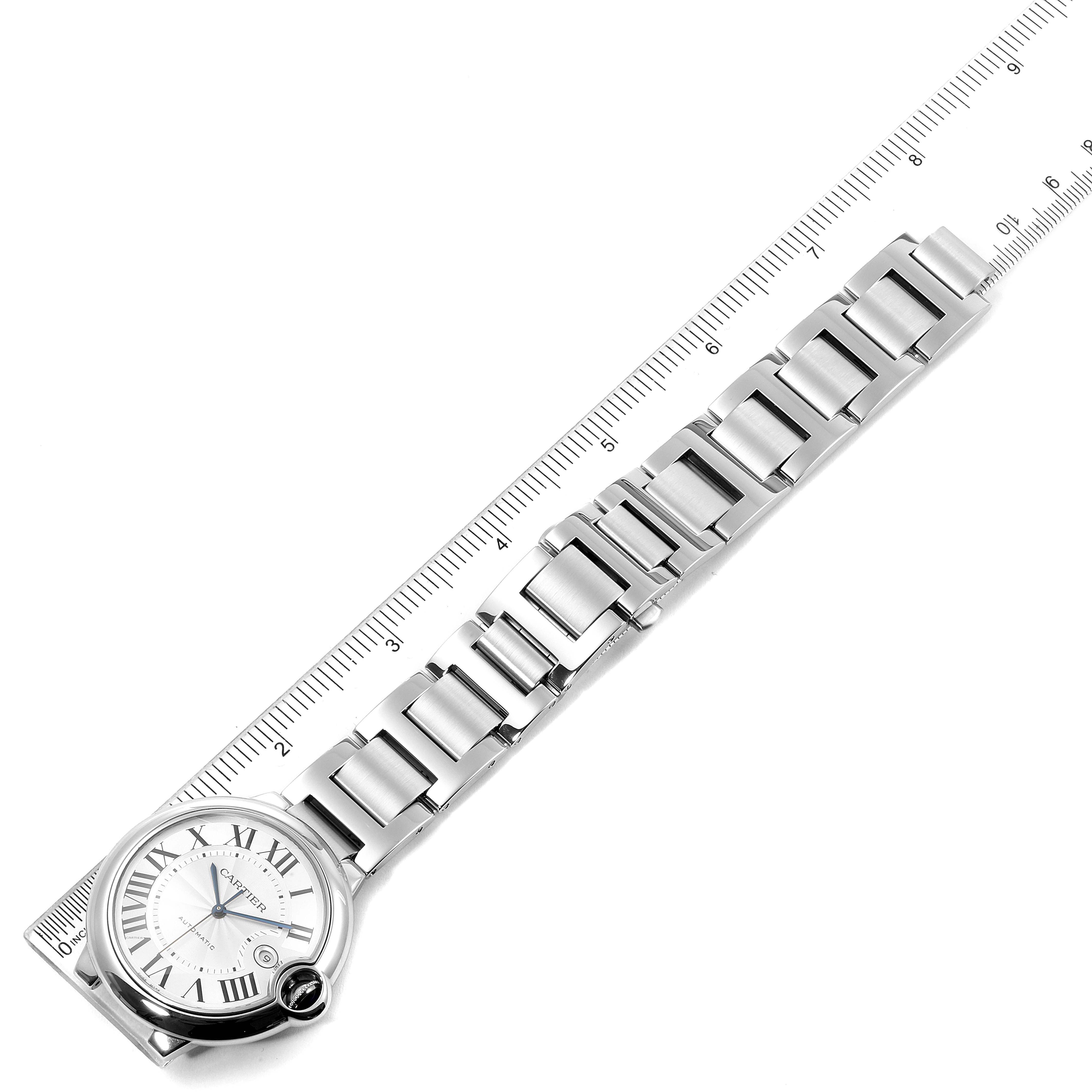 The image shows the Ballon Bleu model watch by Cartier in a top-down angle, highlighting its face, bracelet, and a ruler for size reference.