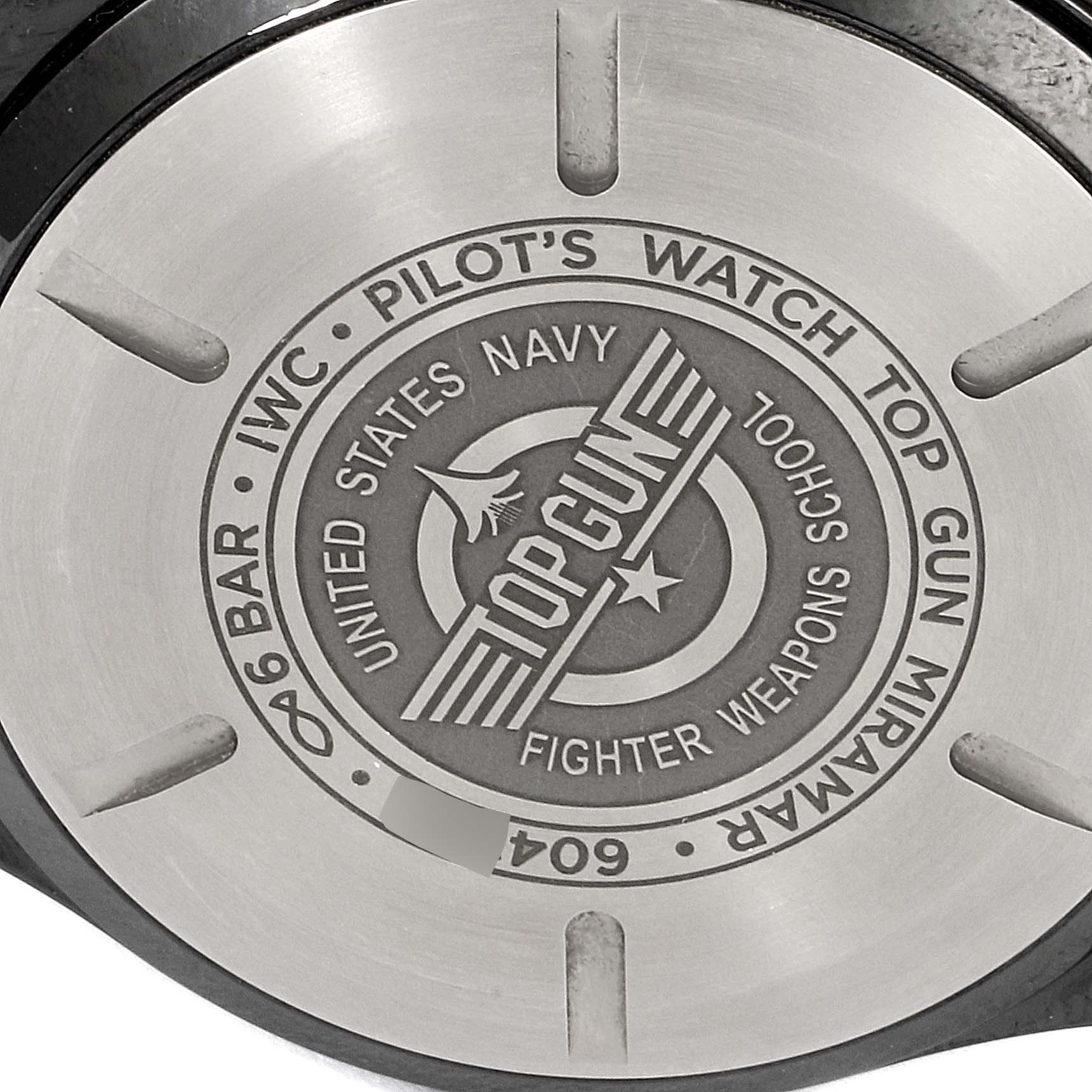 The image shows the case back of an IWC Pilot IW389002 Men's Titanium Black Dial IW389002 Men's Titanium Black Dial model watch, featuring Top Gun and United States Navy engravings.