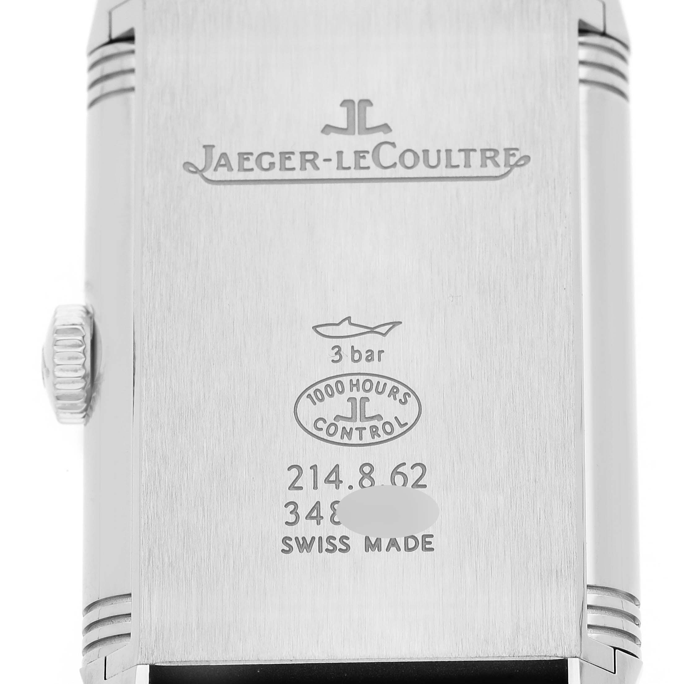 The image shows the back of a Jaeger-LeCoultre Reverso watch with engravings and a crown visible on the side.