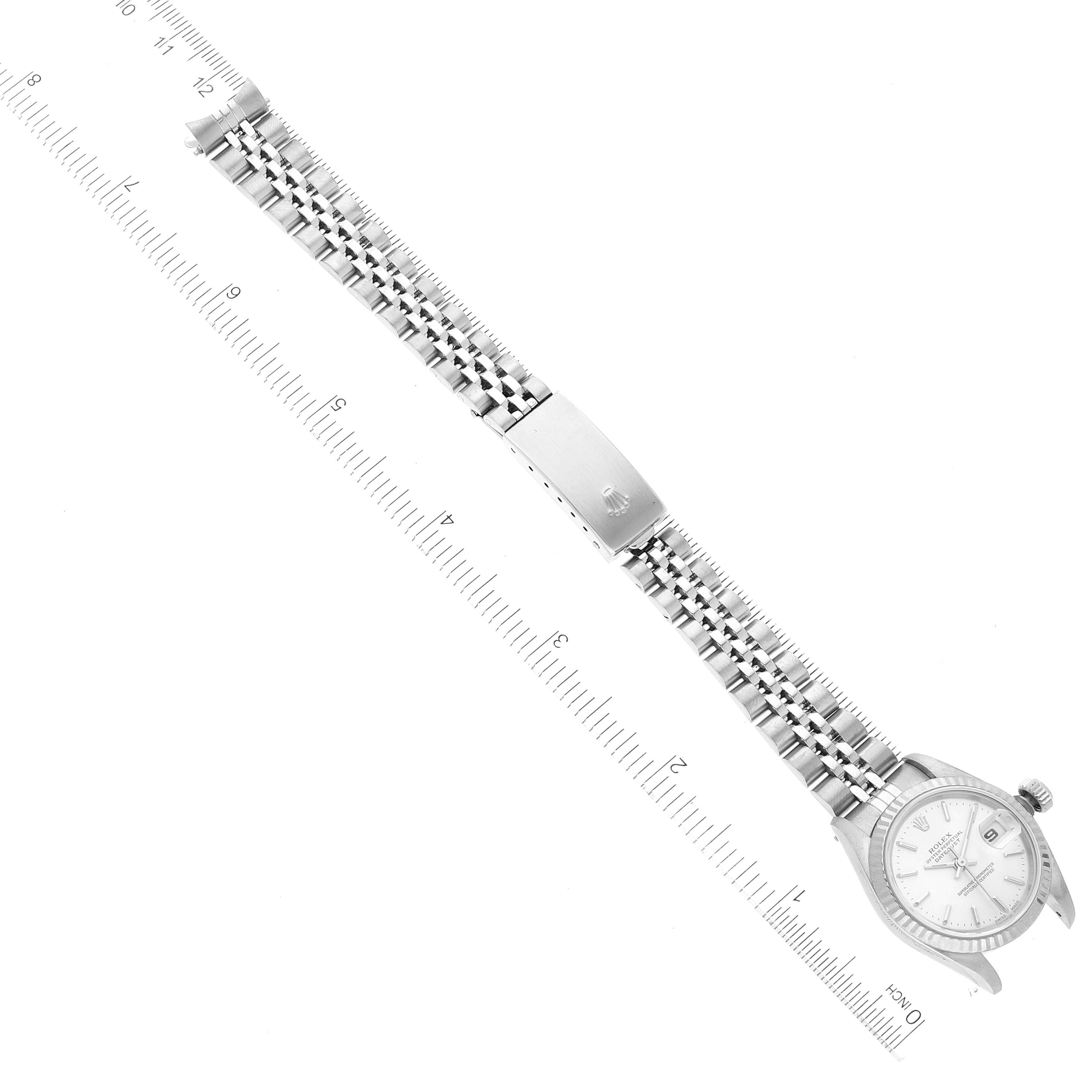 The image shows a top-down view of a Rolex Datejust 79174 Women's Stainless Steel Silver Dial 79174 Women's Stainless Steel Silver Dial watch, displaying the face, bracelet, and clasp next to a measuring scale.