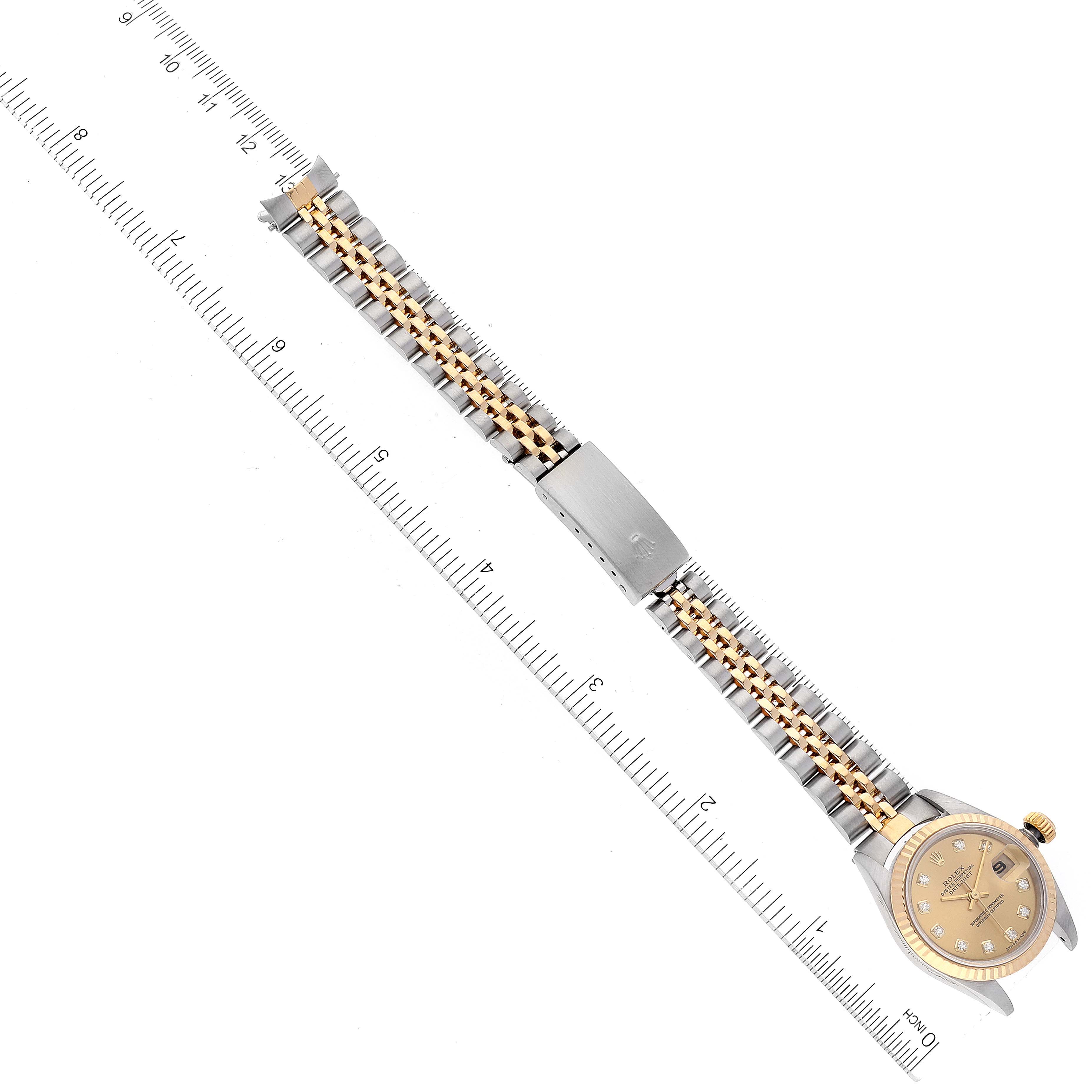 This image shows a top view of a Rolex Datejust 79173 Women's Steel and Gold (two tone) Champagne Dial 79173 Women's Steel and Gold (two tone) Champagne Dial watch with a two-tone bracelet beside a ruler for size reference.