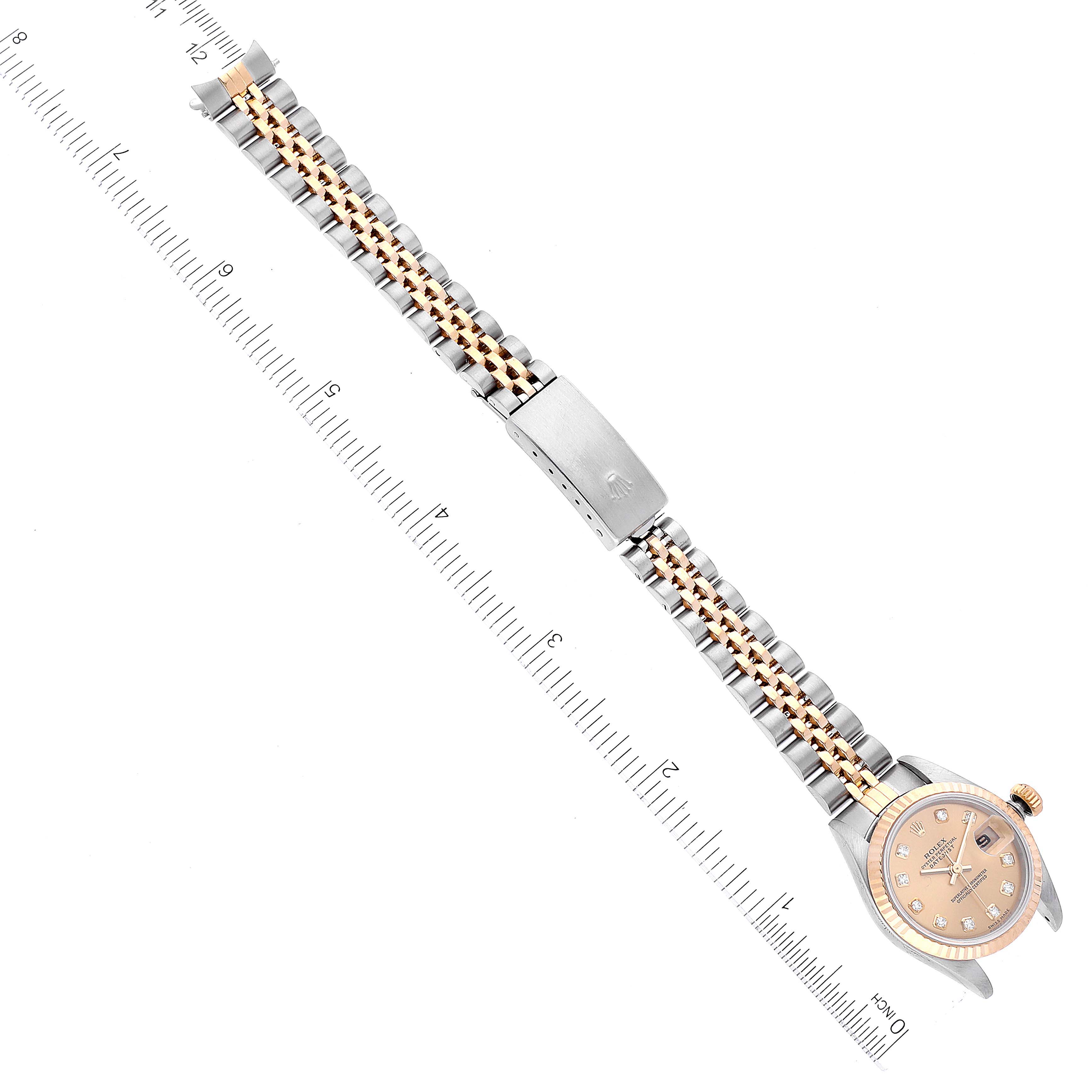 The image shows a Rolex Datejust 79173 Women's Steel and Gold (two tone) Champagne Dial 79173 Women's Steel and Gold (two tone) Champagne Dial watch from a top view, highlighting its dial, bracelet, and clasp alongside a ruler for scale.