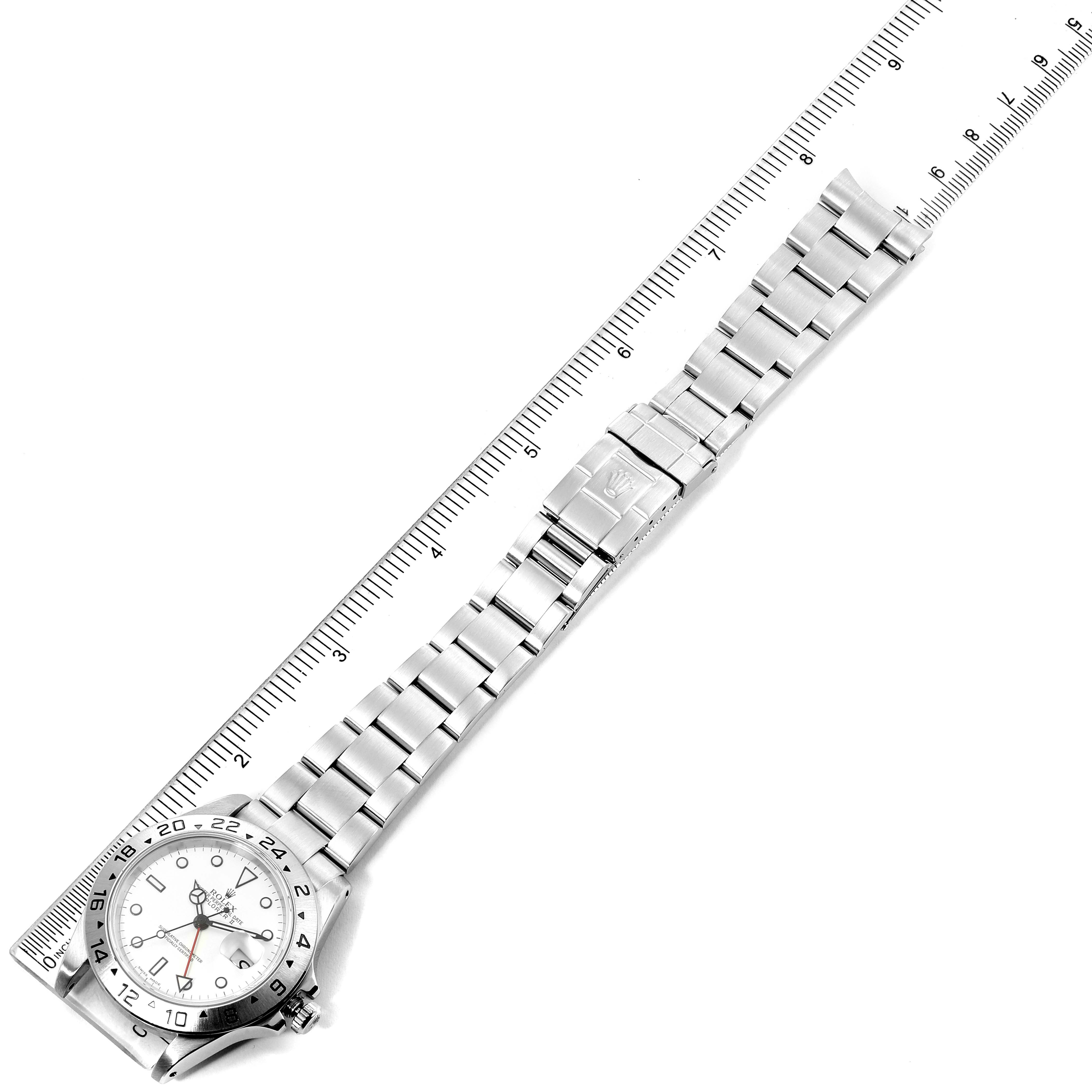 This image shows an overhead view of a Rolex Explorer 16570 Men
s Stainless Steel White Dial 16570 Men
s Stainless Steel White Dial watch and its metal bracelet, laid next to a ruler for measurement.