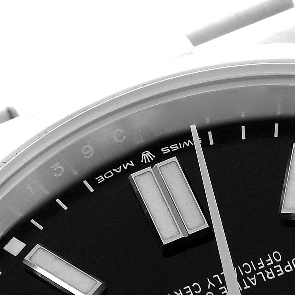 The image shows a close-up of the dial and hour markers of a Rolex Oyster Perpetual 124300 Men's Stainless Steel Black Dial 124300 Men's Stainless Steel Black Dial watch, focusing on the side with branding elements.