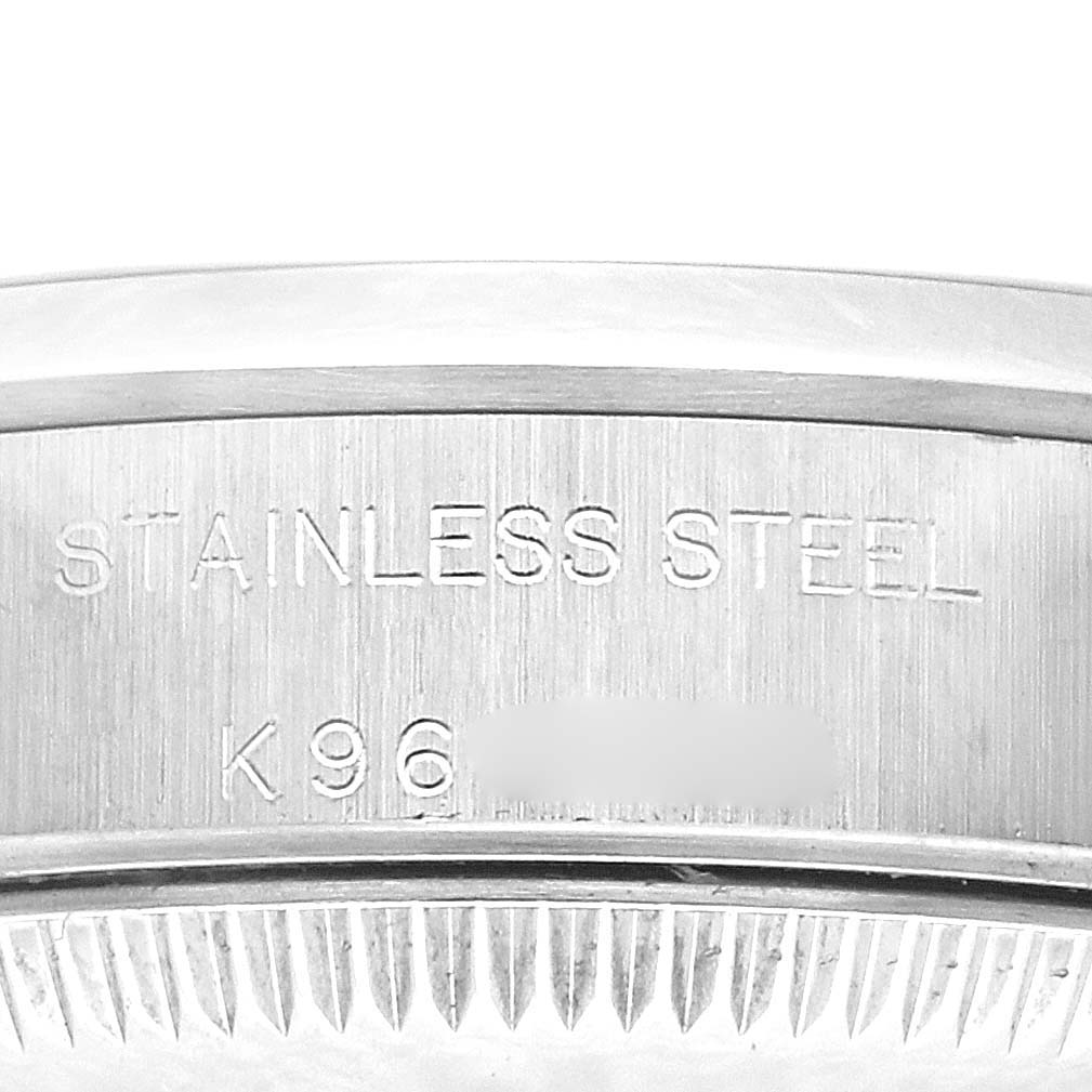 The image shows a close-up of the case back edge of a Rolex Oyster Perpetual 76080 Women's Stainless Steel Orange Dial 76080 Women's Stainless Steel Orange Dial, highlighting the stainless steel engraving.