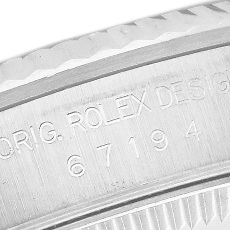 The image shows a close-up of the case side of a Rolex Oyster Perpetual 67194 Women's Steel and Gold (two tone) Orange Dial 67194 Women's Steel and Gold (two tone) Orange Dial, highlighting engraved serial details.