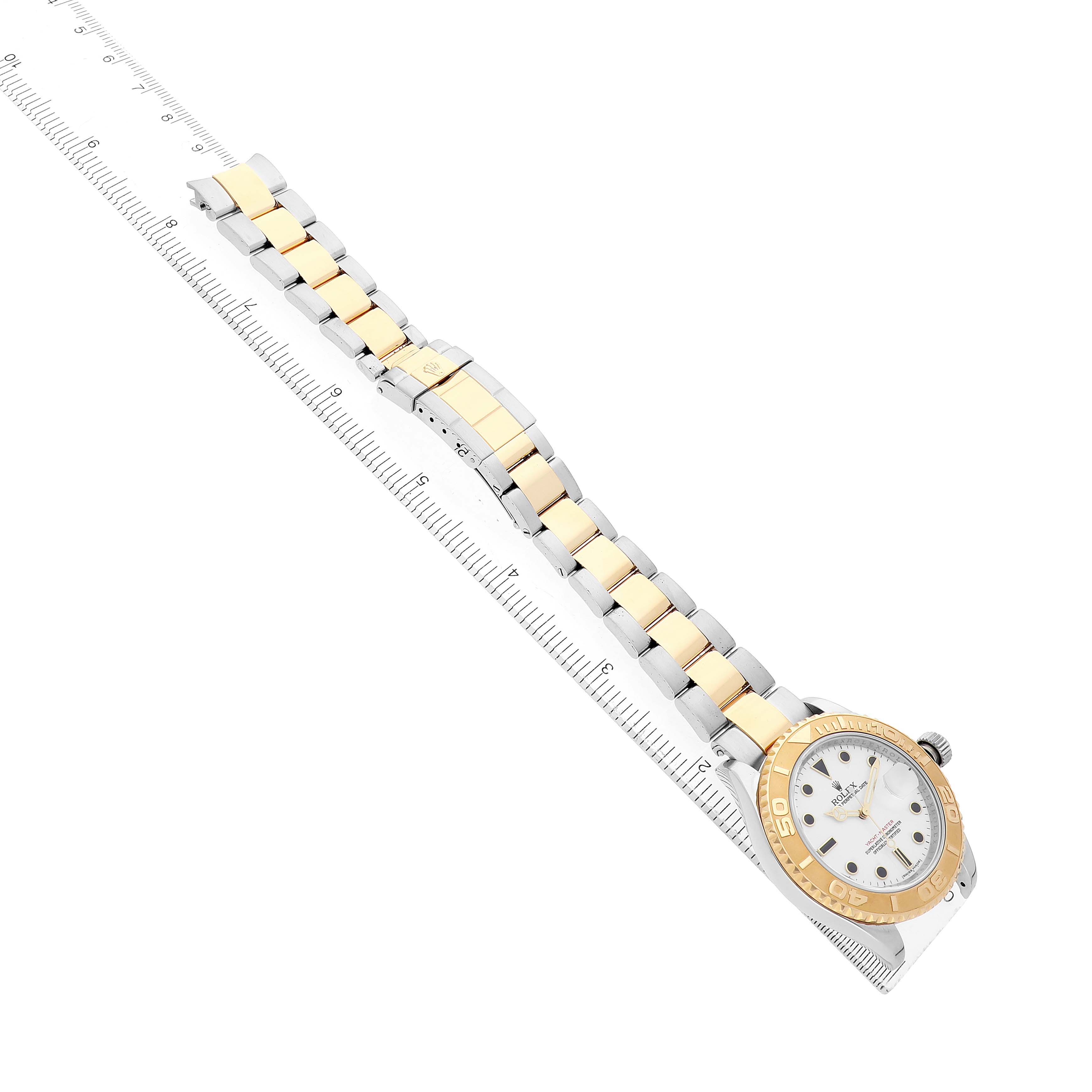 The Rolex Yacht-Master 16623 Men's Steel and Gold (two tone) White Dial watch is shown mostly flat, displaying the band, bezel, and part of the face alongside a ruler.