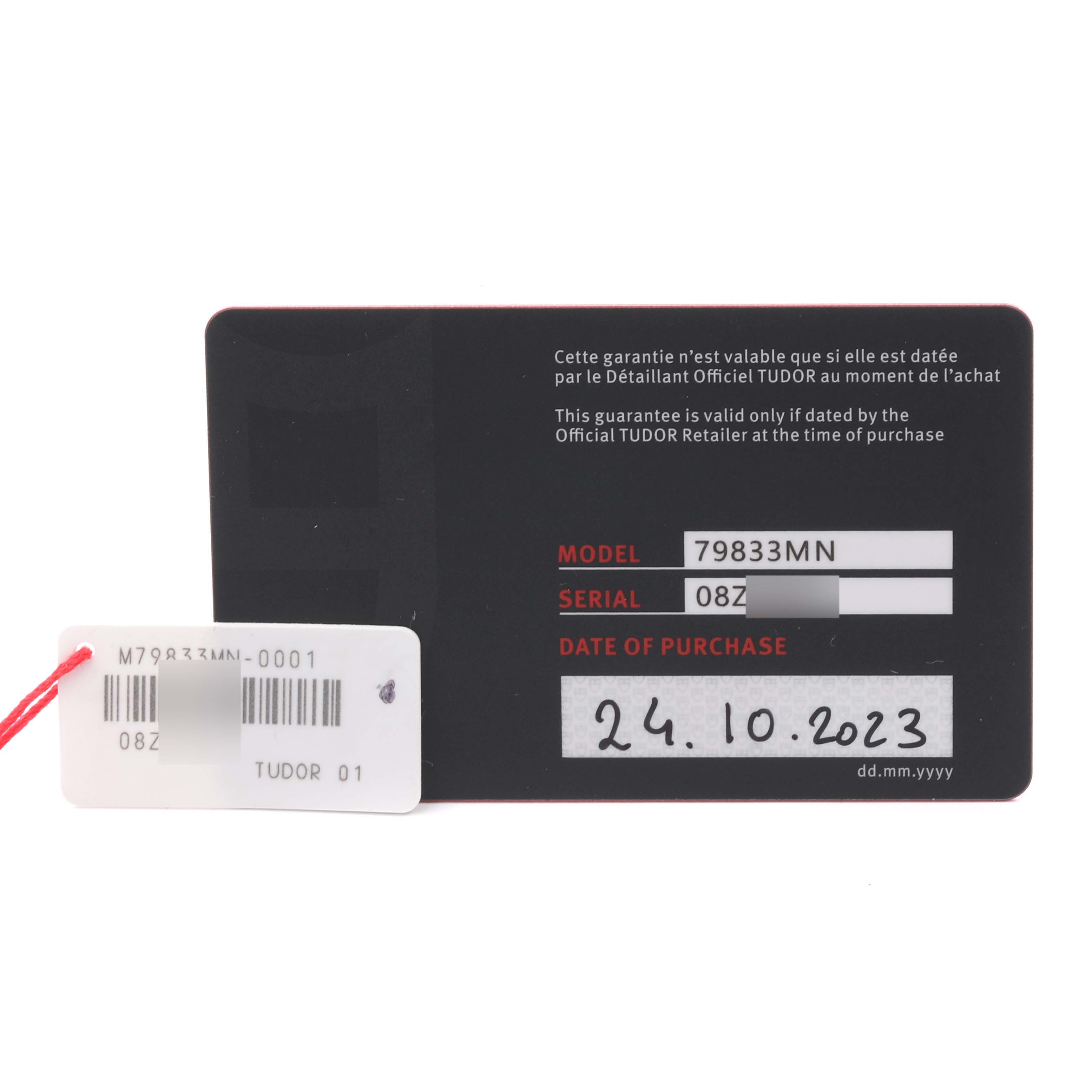 The image shows a warranty card and tag for the Tudor Heritage Black Bay 79833MN Men's Steel and Gold (two tone) Black Dial 79833MN Men's Steel and Gold (two tone) Black Dial, displaying model and serial numbers.