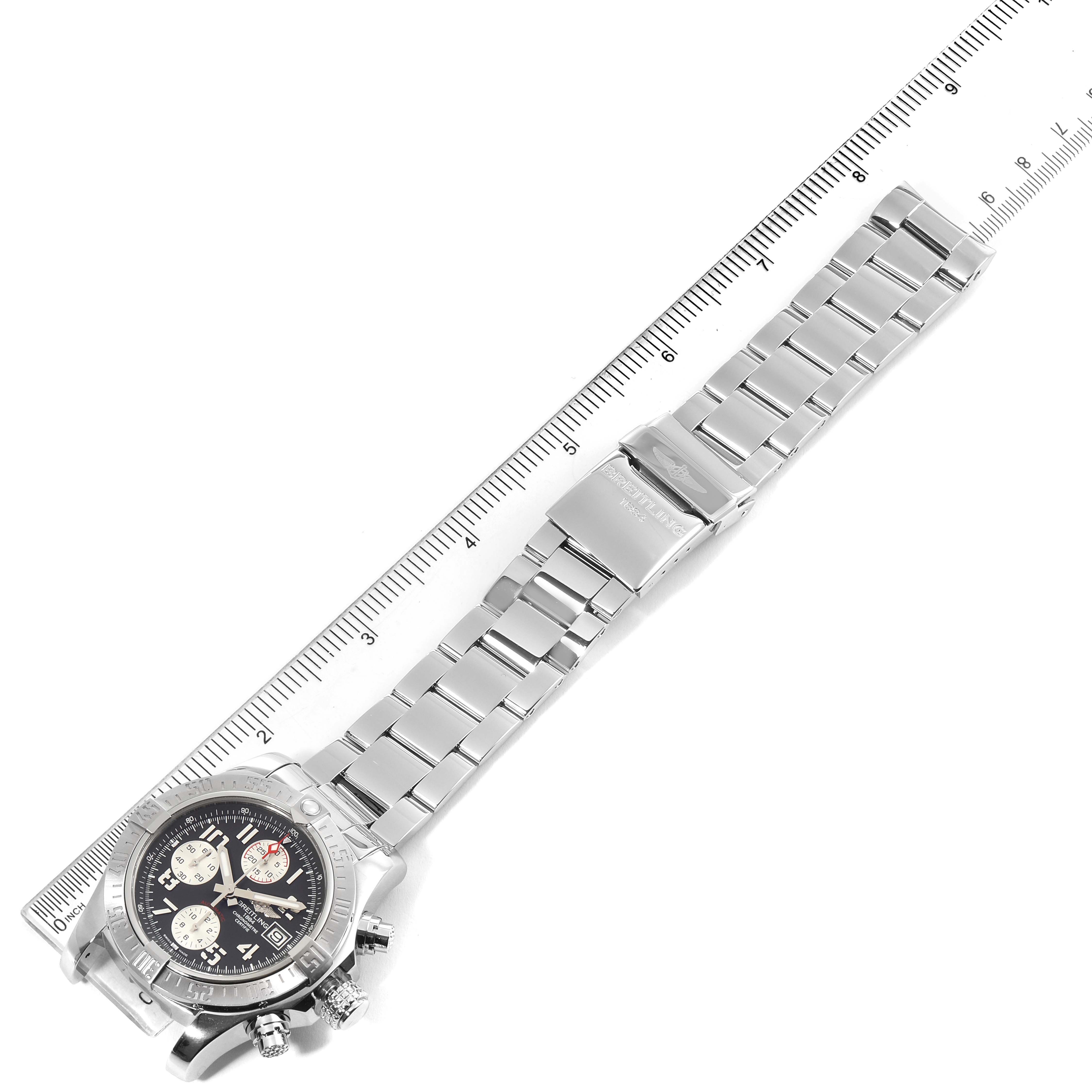 The image shows an overhead angle of a Breitling Avenger A13381 Men's Stainless Steel Grey Dial A13381 Men's Stainless Steel Grey Dial watch, including the dial, bezel, bracelet, and clasp, next to a ruler for scale.