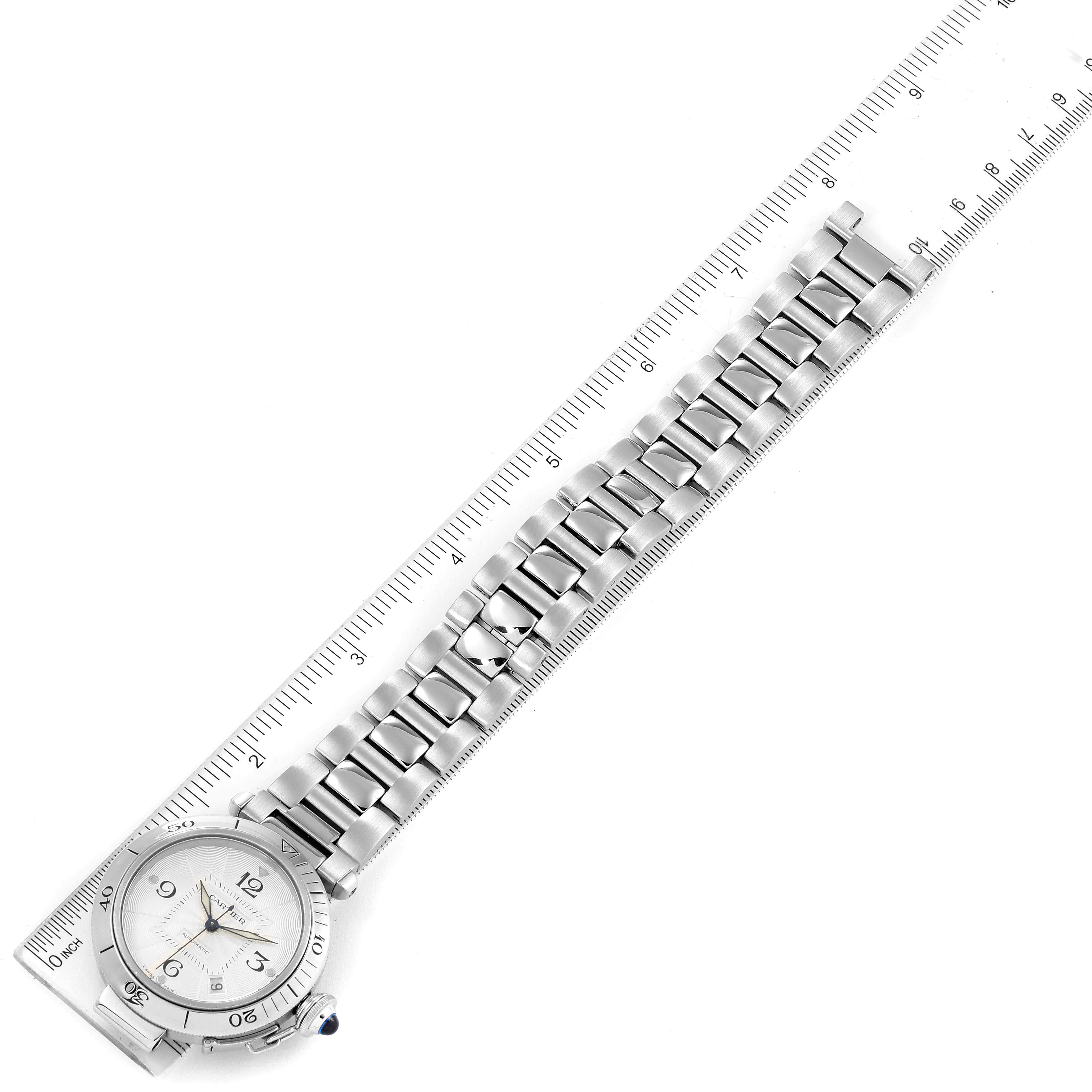 The image shows a top view of a Cartier Pasha W31059H3 Men
s Stainless Steel Silver Dial W31059H3 Men
s Stainless Steel Silver Dial watch with its metal bracelet aligned with a ruler.