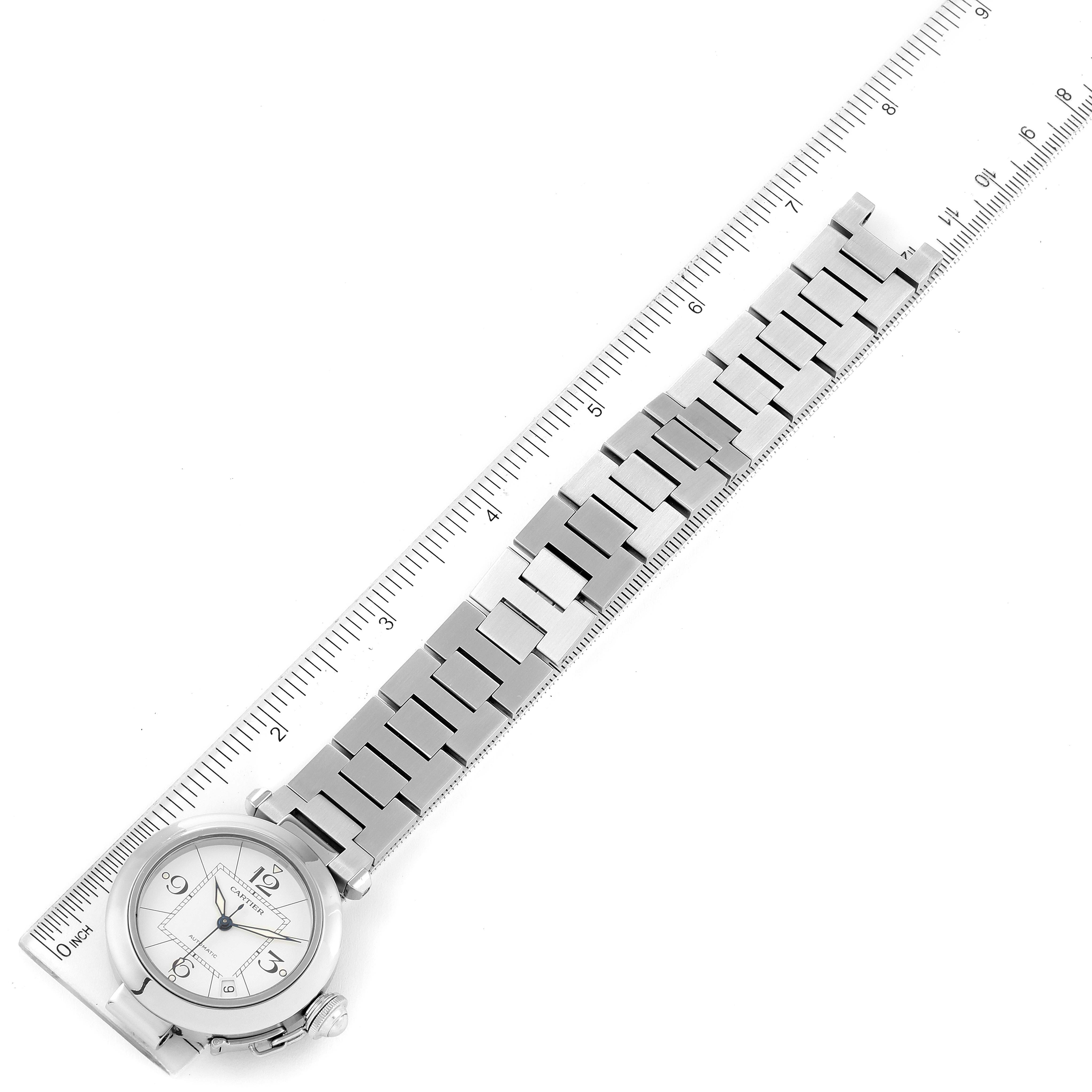 The Cartier Pasha W31074M7 Men's Stainless Steel White Dial W31074M7 Men's Stainless Steel White Dial watch is shown from a top view, with both the face and metal bracelet fully visible, alongside a ruler for scale.