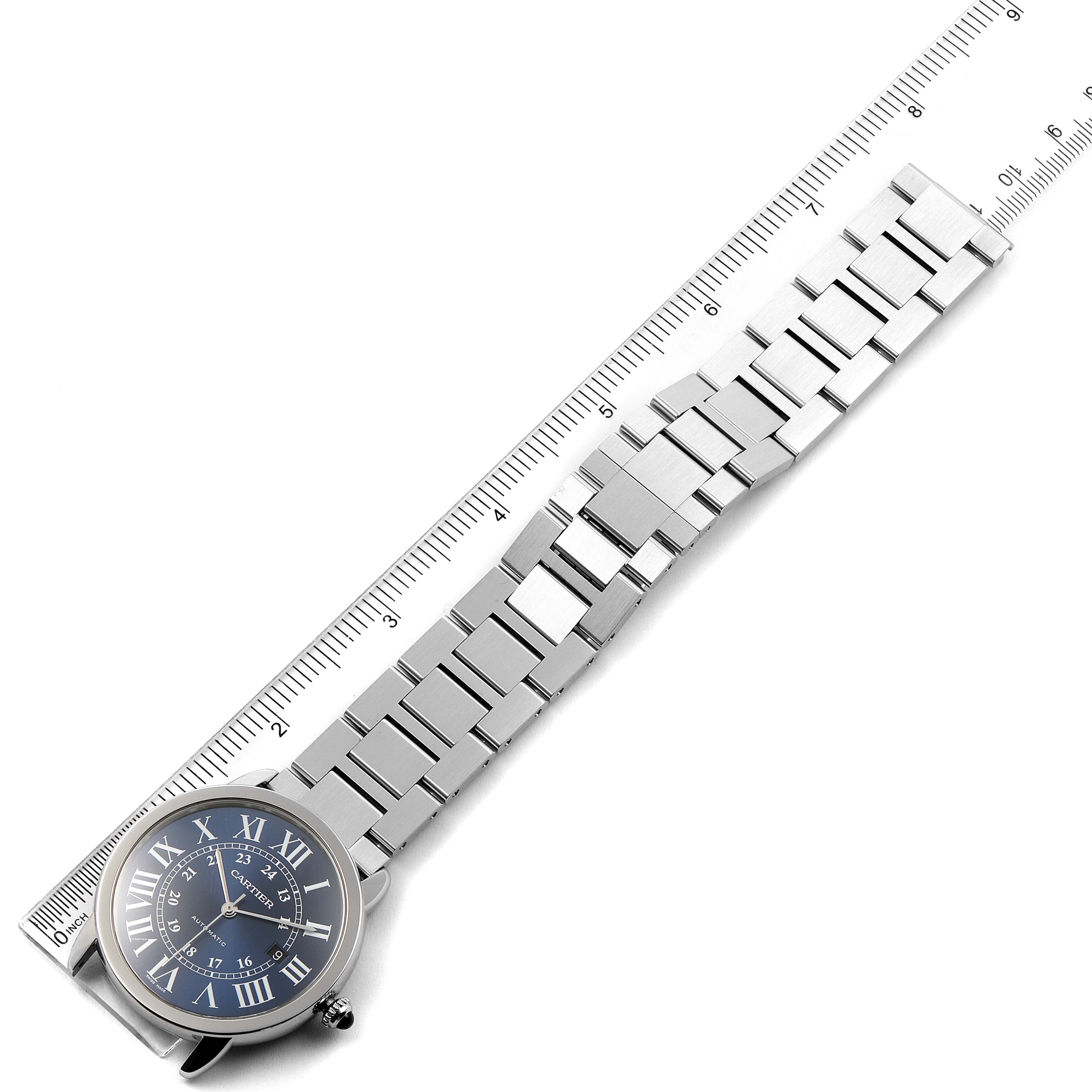 The image shows an overhead view of a Ronde model Cartier watch, highlighting its face and metal bracelet next to a ruler.