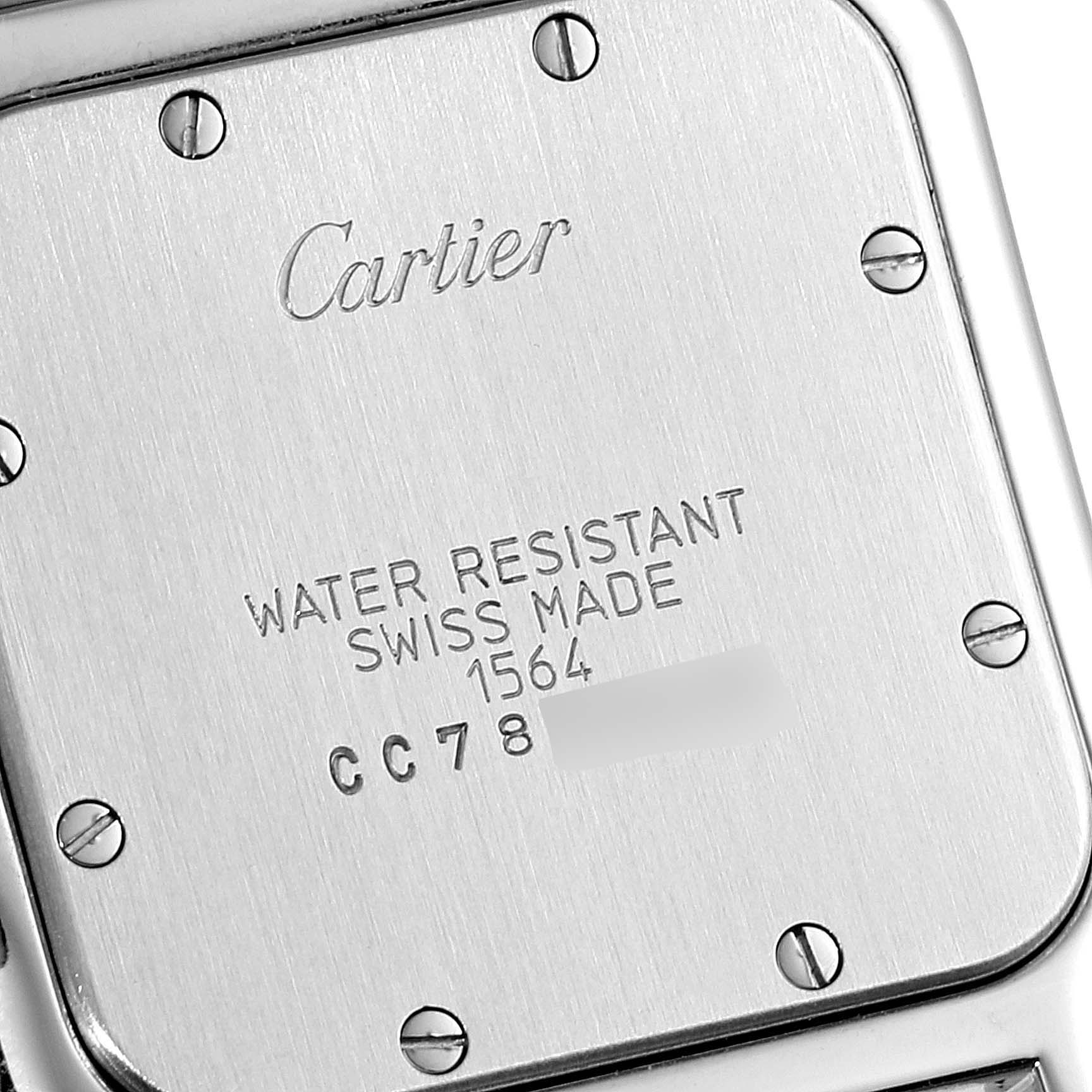 The image shows the back case of a Santos model watch by Cartier, displaying screws and etched text details.