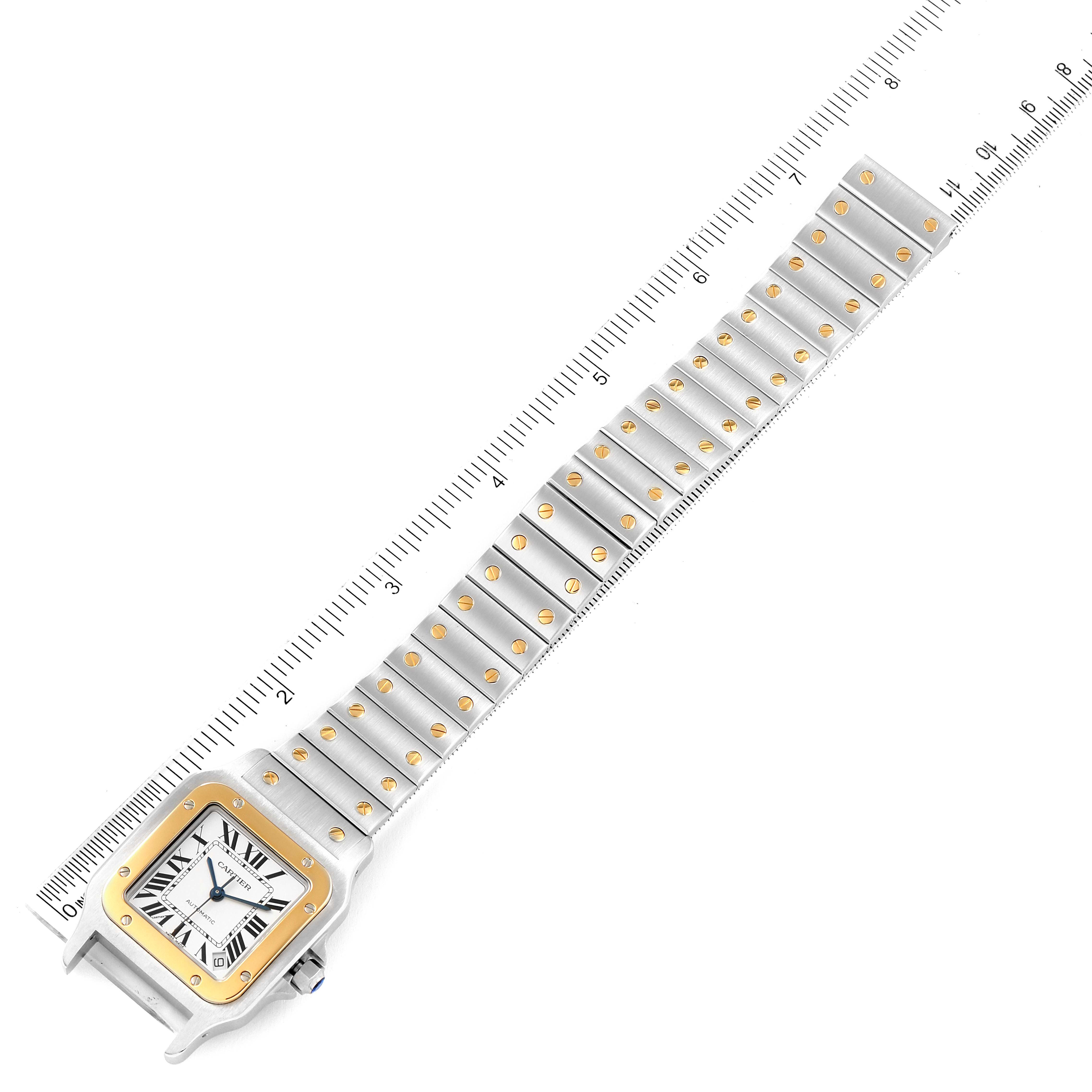 The image shows a Santos model by Cartier watch laid flat with a ruler, displaying the watch face and bracelet.