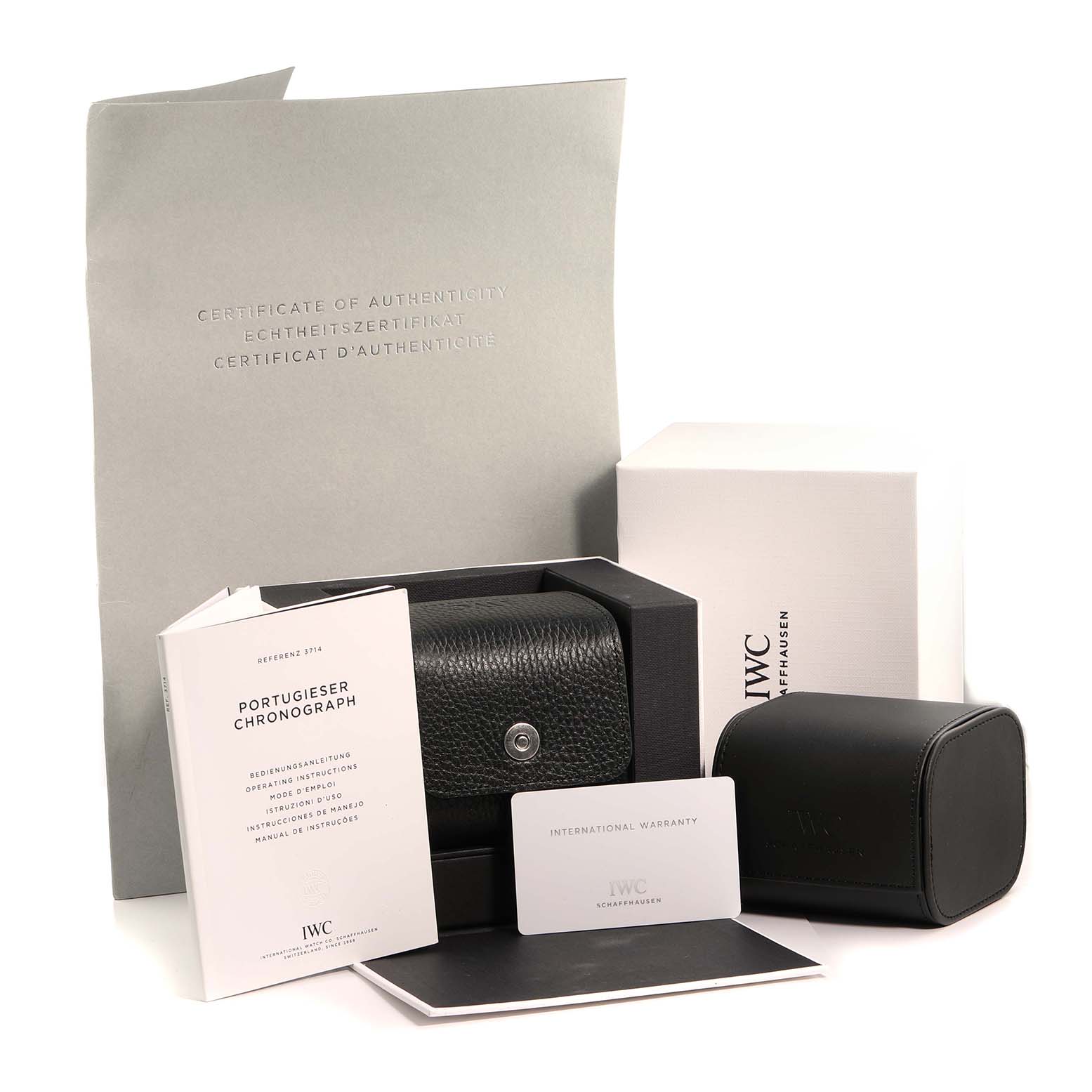 The image shows accessories for an IWC Portuguese IW371447 Men's Stainless Steel Black Dial model, including a leather case, warranty card, manual, and certificate at an angled view.