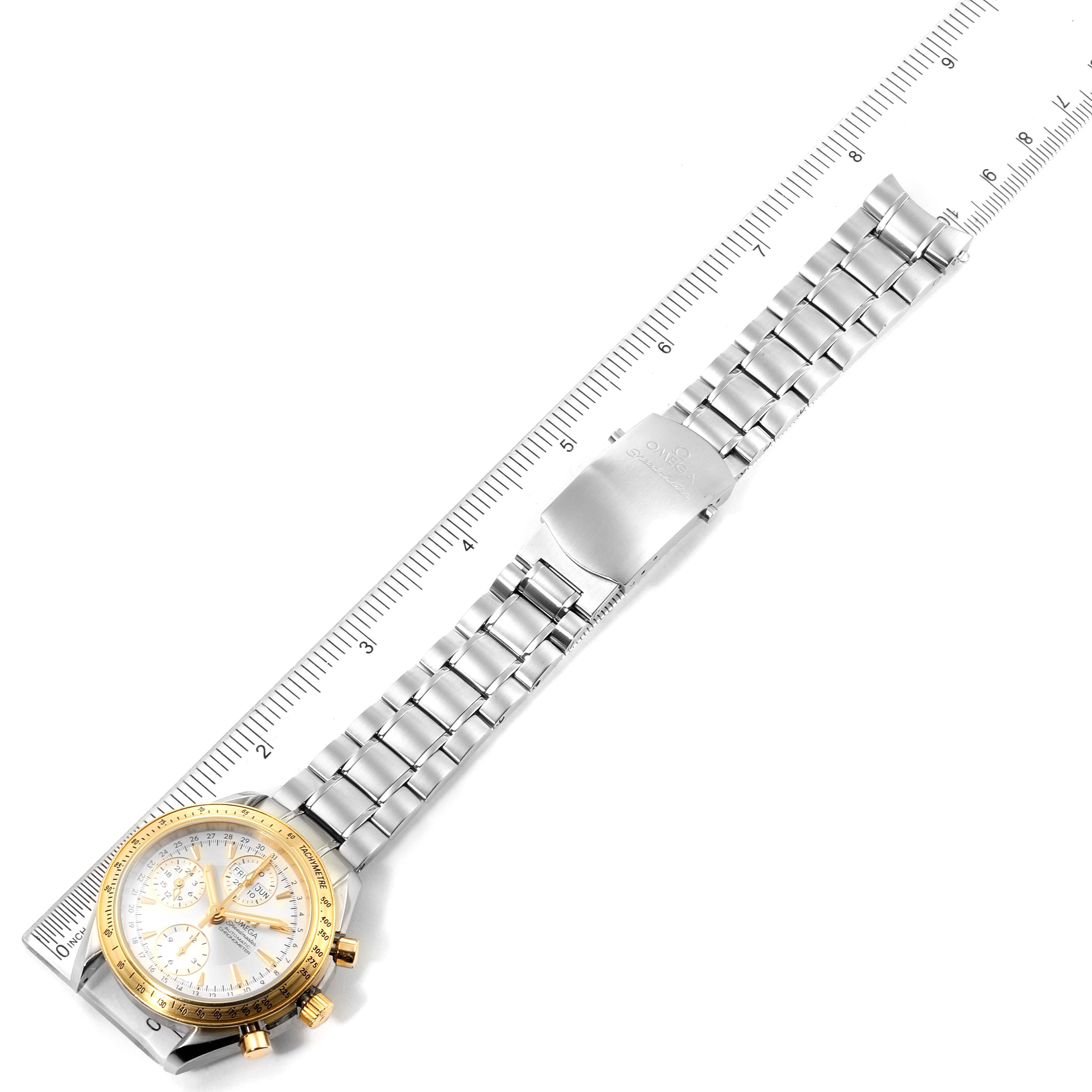 The image shows the entire watch and band of an Omega Speedmaster 323.21.40.44.02.001 Men's Steel and Gold (two tone) Silver Dial 323.21.40.44.02.001 Men's Steel and Gold (two tone) Silver Dial laid flat next to a ruler, highlighting its length and metal bracelet.