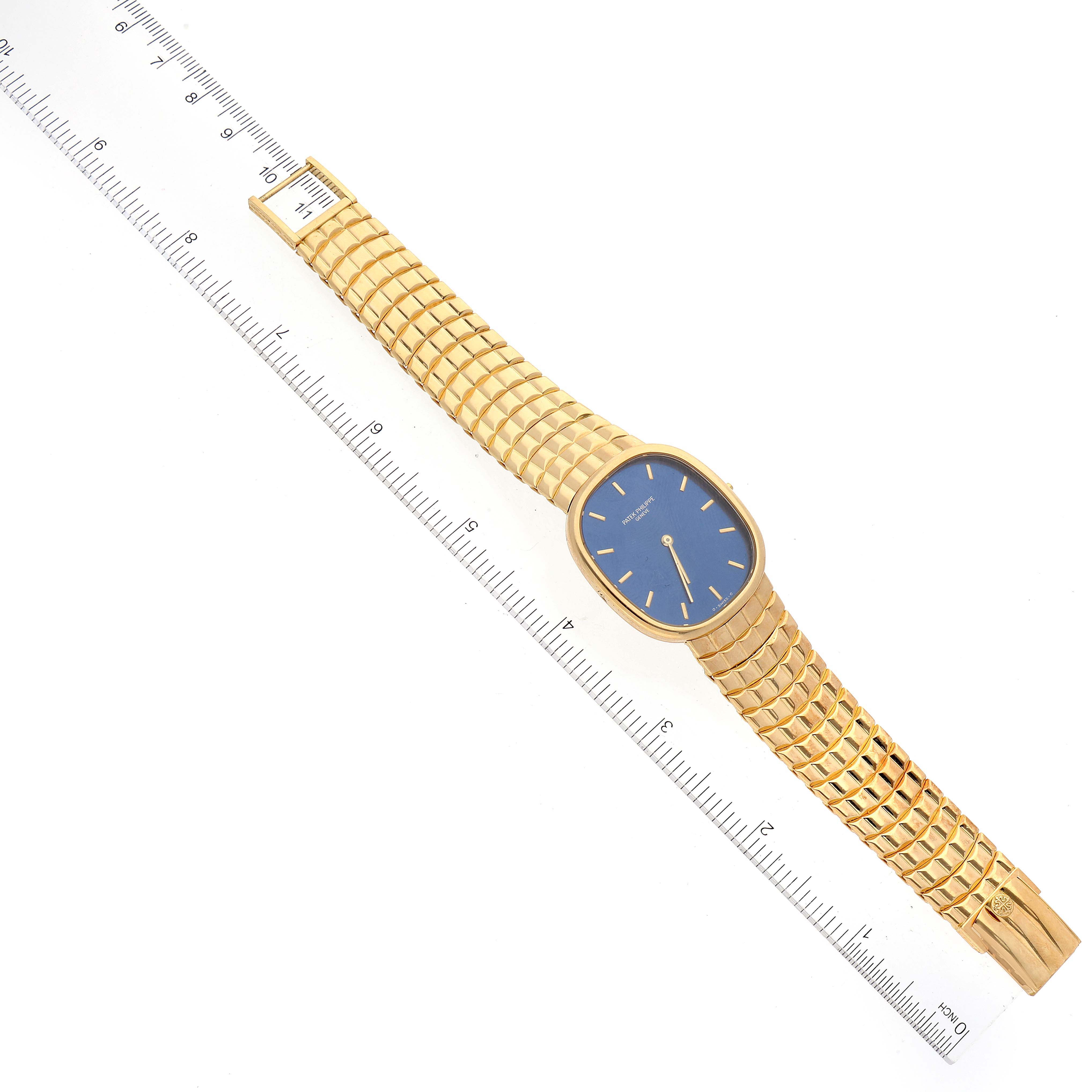 The image shows a top-down view of the Patek Philippe Golden Ellipse 3738 Men's Yellow Gold Blue Dial 3738 Men's Yellow Gold Blue Dial watch with its band extended and a ruler alongside.