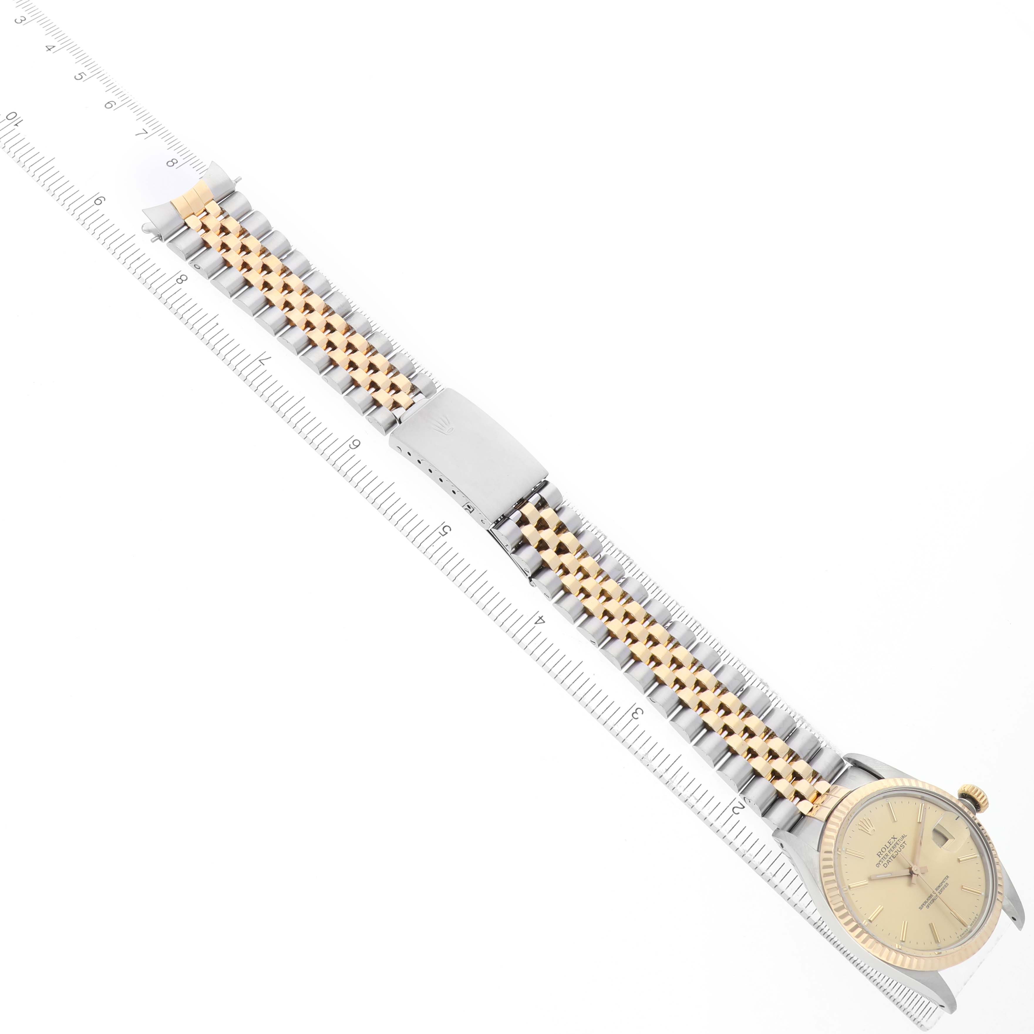 The Rolex Datejust 16013 Men's Stainless Steel Champagne Dial watch is shown from an overhead view, highlighting the face, bracelet, and clasp alongside a ruler for scale.