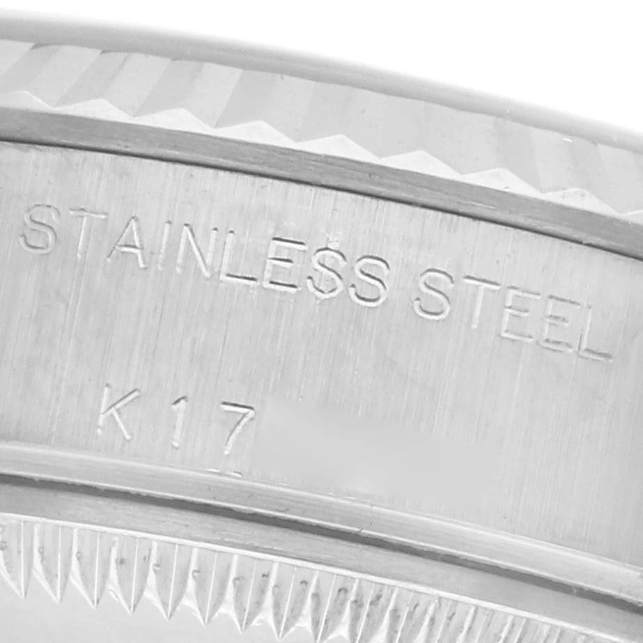 The image shows a close-up of the edge of a Rolex Datejust 79174 Women's Stainless Steel Silver Dial watch, highlighting the engraved "STAINLESS STEEL" and part of the fluted bezel.