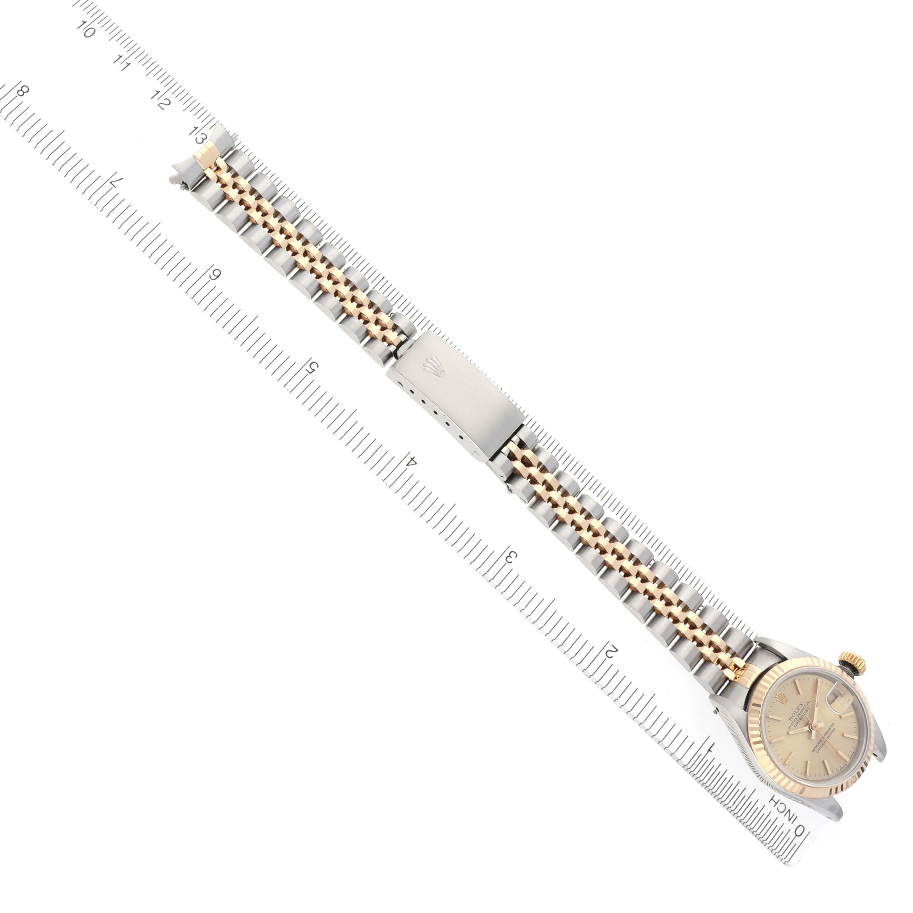 The Rolex Datejust 69173 Women's Steel and Gold (two tone) Champagne Dial 69173 Women's Steel and Gold (two tone) Champagne Dial watch is shown from a top view, displaying the dial, bracelet, and clasp with a ruler for scale.