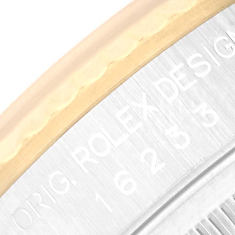 This is a close-up of the inner bezel and edge of the crystal of a Rolex Datejust 16233 Men's Steel and Gold (two tone) Silver Dial 16233 Men's Steel and Gold (two tone) Silver Dial watch, showing part of the "Rolex" engraving.