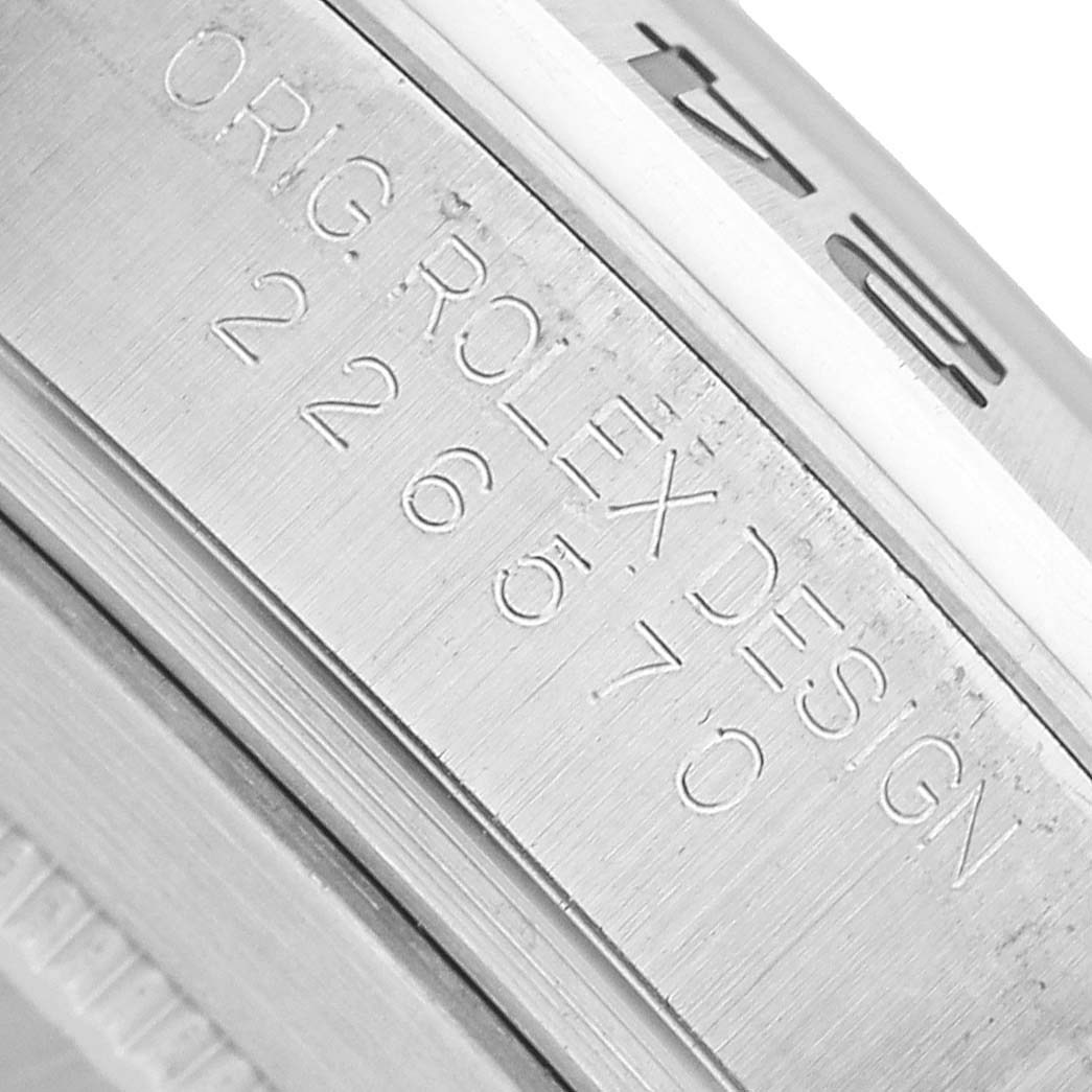 The image shows a close-up of the Rolex Explorer 226570 Men's Stainless Steel Black Dial watch case with engraved text along the side.