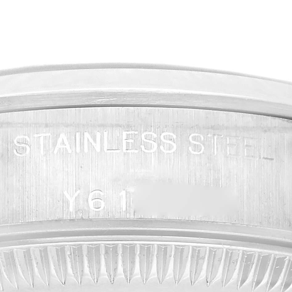 The image shows a close-up of the side of a Rolex Oyster Perpetual 76080 Women's Stainless Steel Black Dial 76080 Women's Stainless Steel Black Dial watch case with "STAINLESS STEEL" and some numbers engraved.