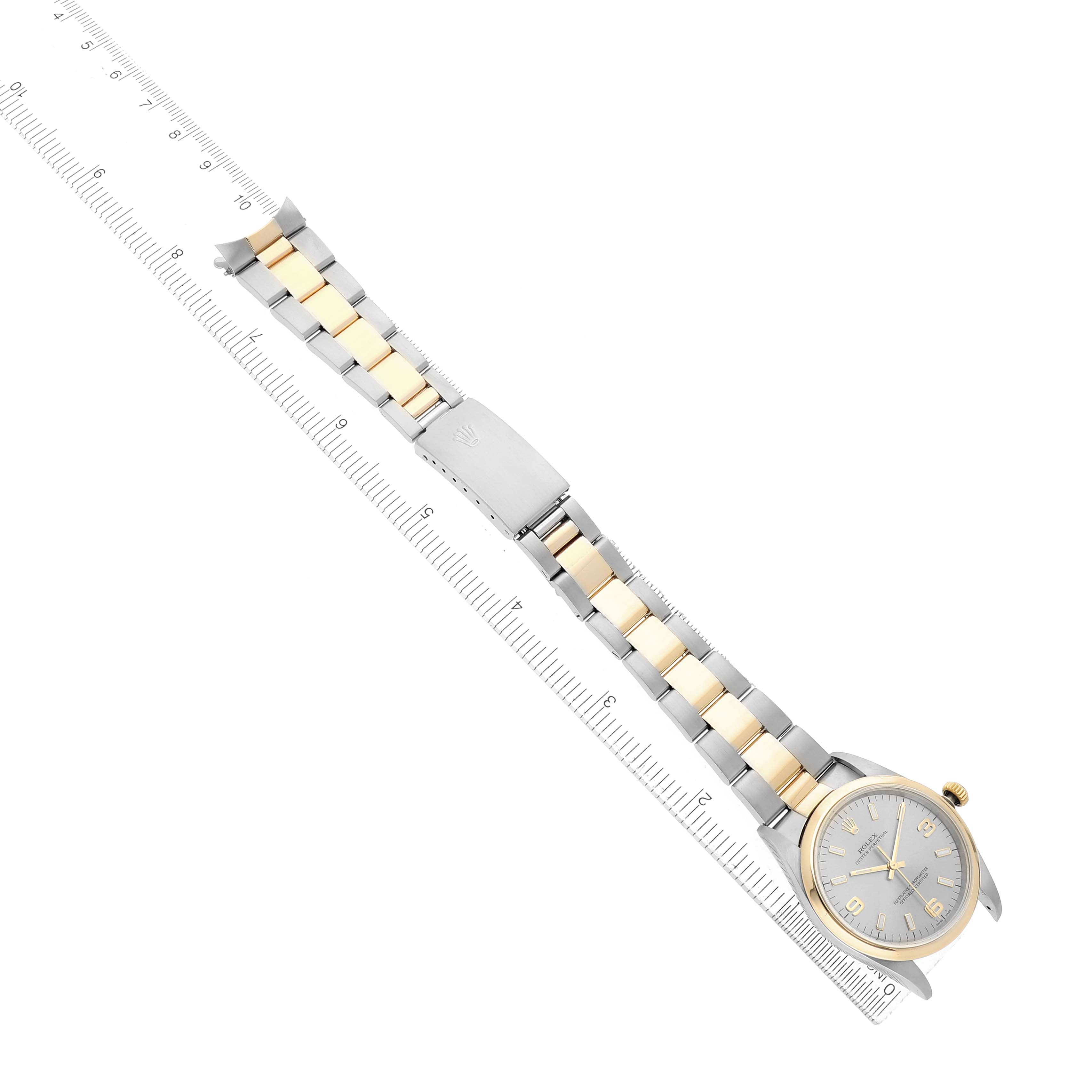 The Rolex Oyster Perpetual 14203 Men's Steel and Gold (two tone) Silver Dial watch is shown at an angle with its full band and clasp visible, alongside a ruler for scale.