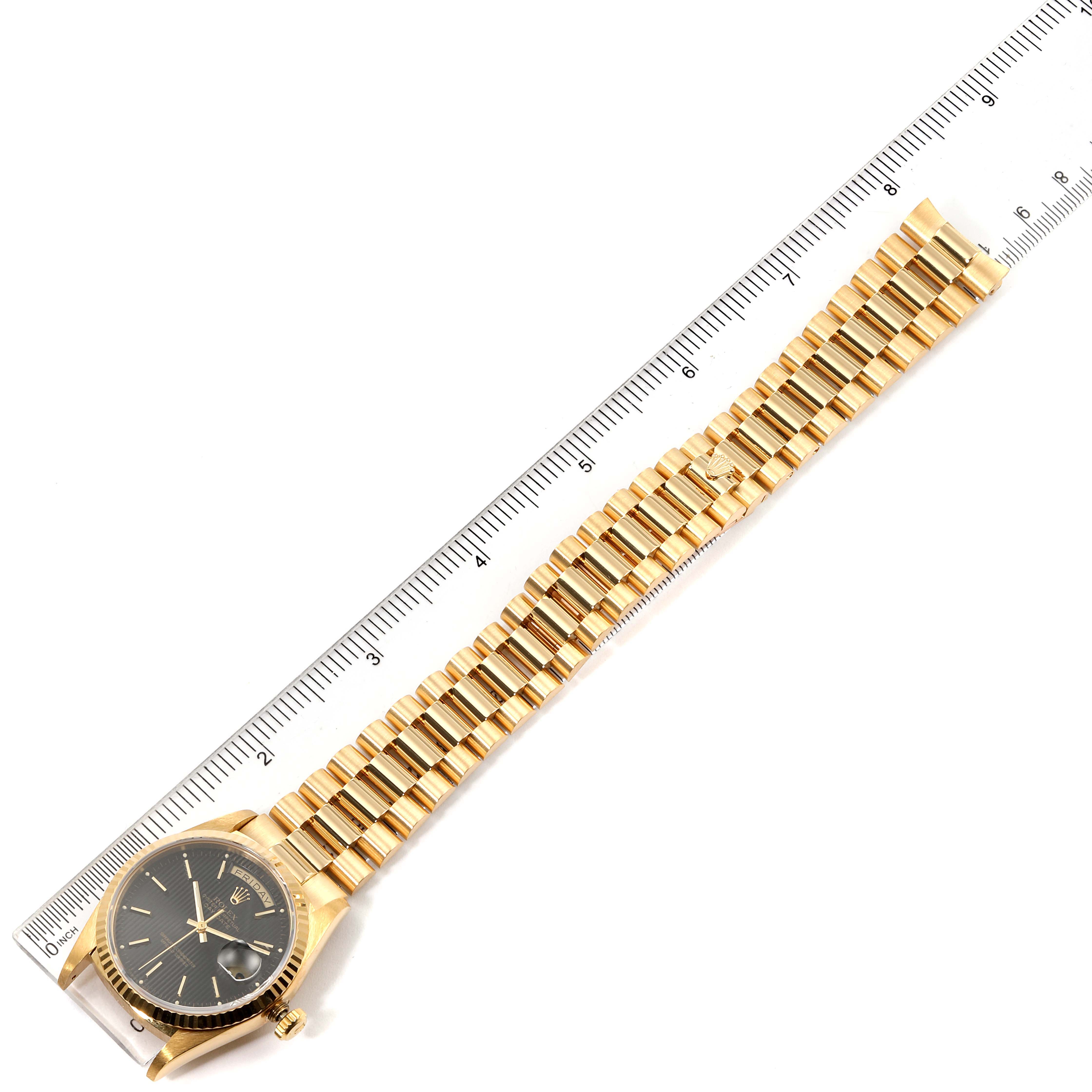 The image shows a Rolex President 18238 Men's Yellow Gold Black Dial 18238 Men's Yellow Gold Black Dial model watch laid flat next to a ruler, displaying its face and gold bracelet.