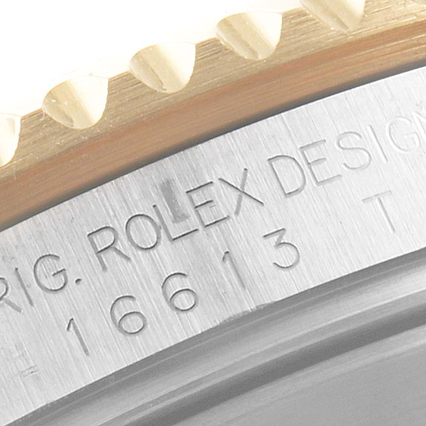 The image shows a close-up of the Rolex Submariner 16613 Men
s Steel and Gold (two tone) Grey Dial 16613 Men
s Steel and Gold (two tone) Grey Dial
s bezel and part of the engraved case.