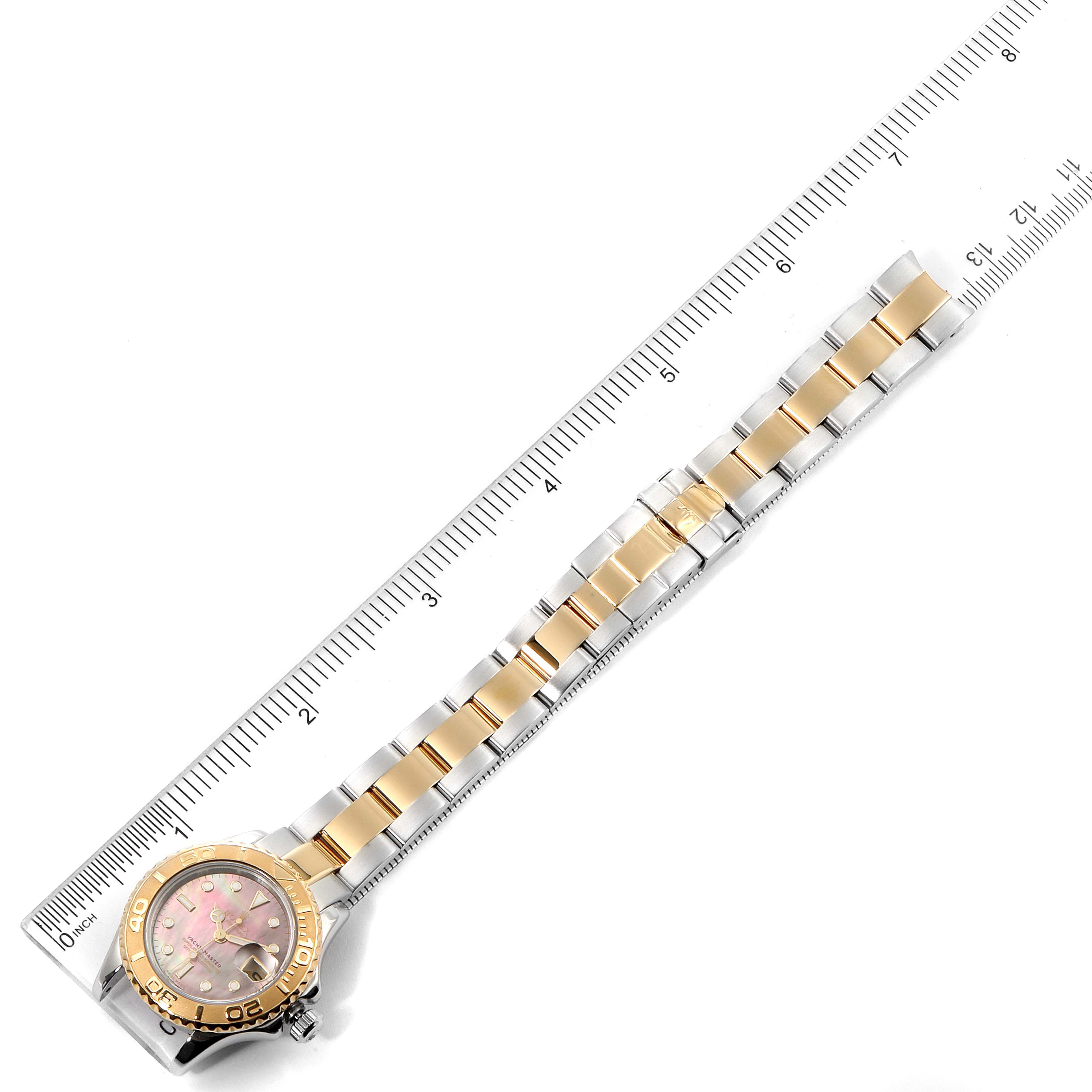 The Rolex Yacht-Master 169623 Women's Steel and Gold (two tone) Mother of Pearl Dial 169623 Women's Steel and Gold (two tone) Mother of Pearl Dial watch is shown from a top-down angle, featuring its bracelet and dial against a measuring ruler.