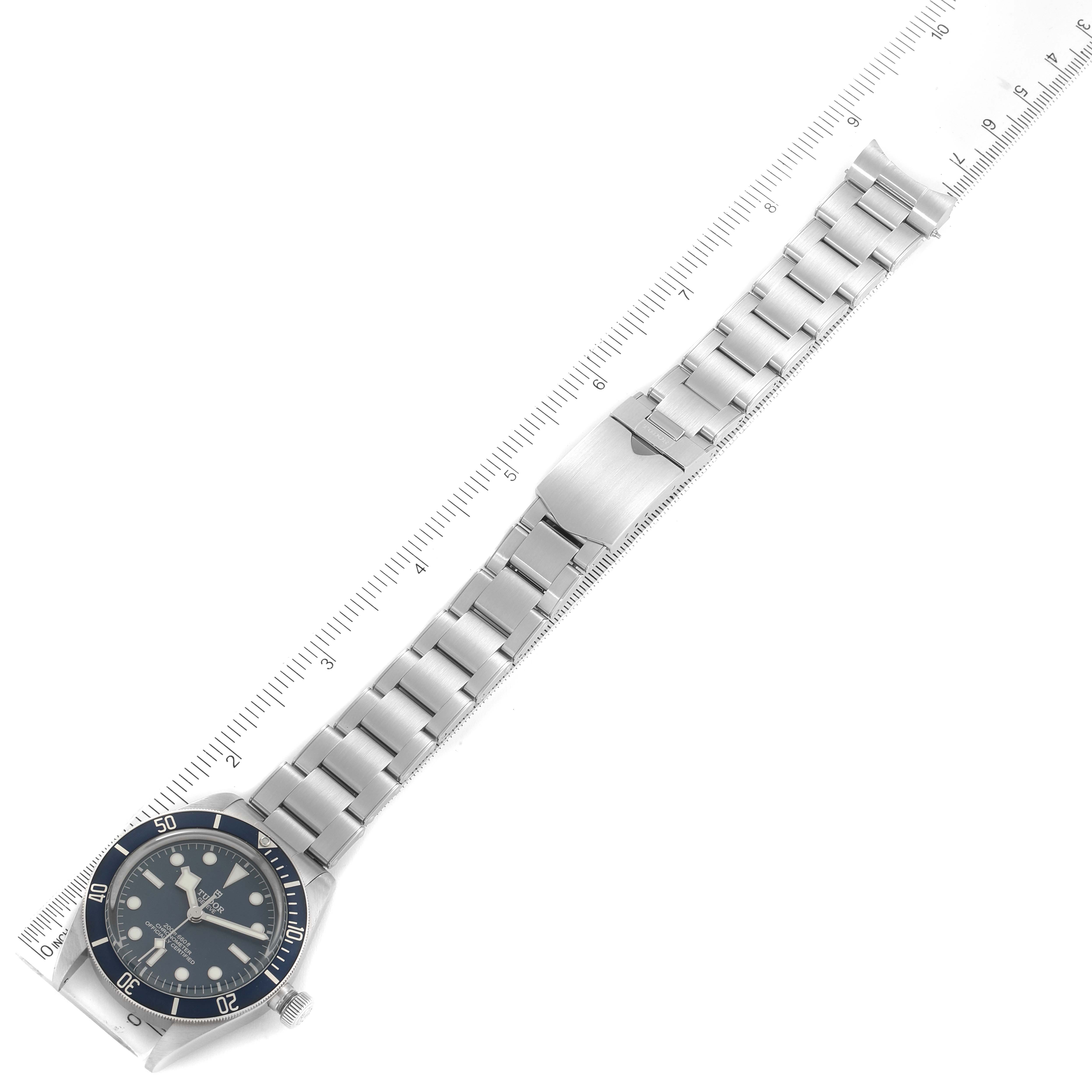 The Tudor Heritage Black Bay 79030B Men
s Stainless Steel Blue Dial 79030B Men
s Stainless Steel Blue Dial watch is shown from a top angle, displaying the face, bezel, and full metal bracelet laid along a ruler.