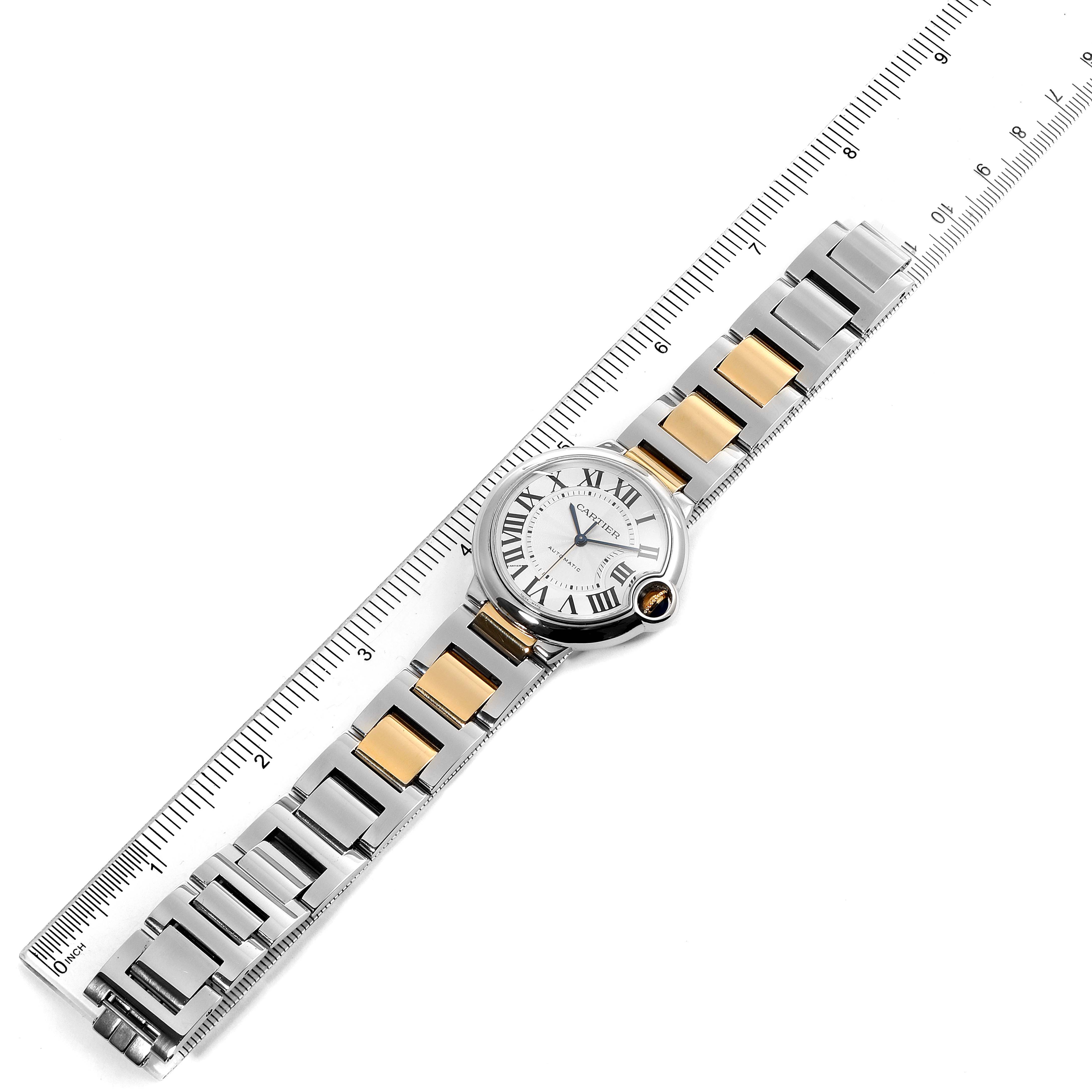 The image shows a top view of a Cartier Ballon Bleu W2BB0012 Women's Steel and Gold (two tone) Silver Dial W2BB0012 Women's Steel and Gold (two tone) Silver Dial watch with a two-tone metal bracelet placed beside a ruler for scale.