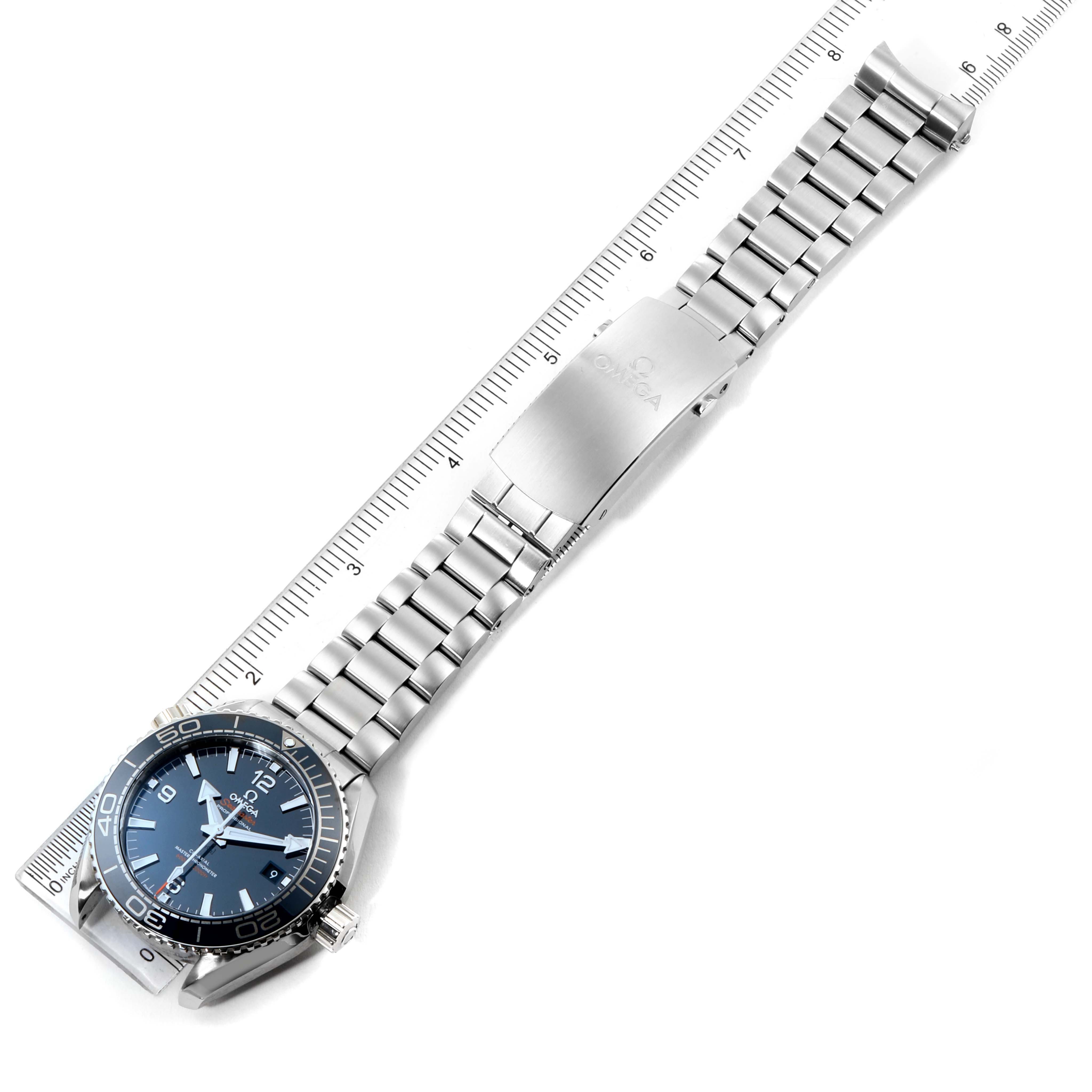 The image shows an Omega Planet Ocean 215.30.44.21.03.001 Men's Stainless Steel Blue Dial 215.30.44.21.03.001 Men's Stainless Steel Blue Dial watch laid flat with its band fully extended next to a ruler for scale.