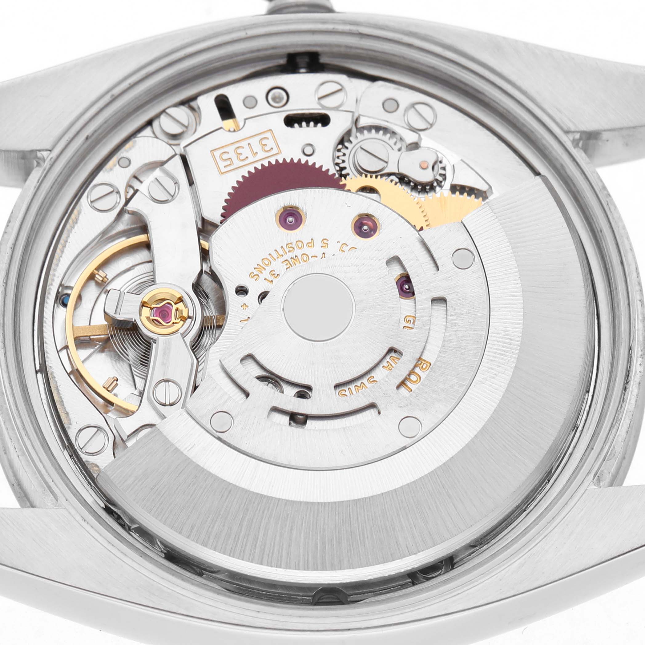 The image shows the movement from the back of a Rolex Date 115210 Men's Stainless Steel Silver Dial, displaying its intricate mechanical components.